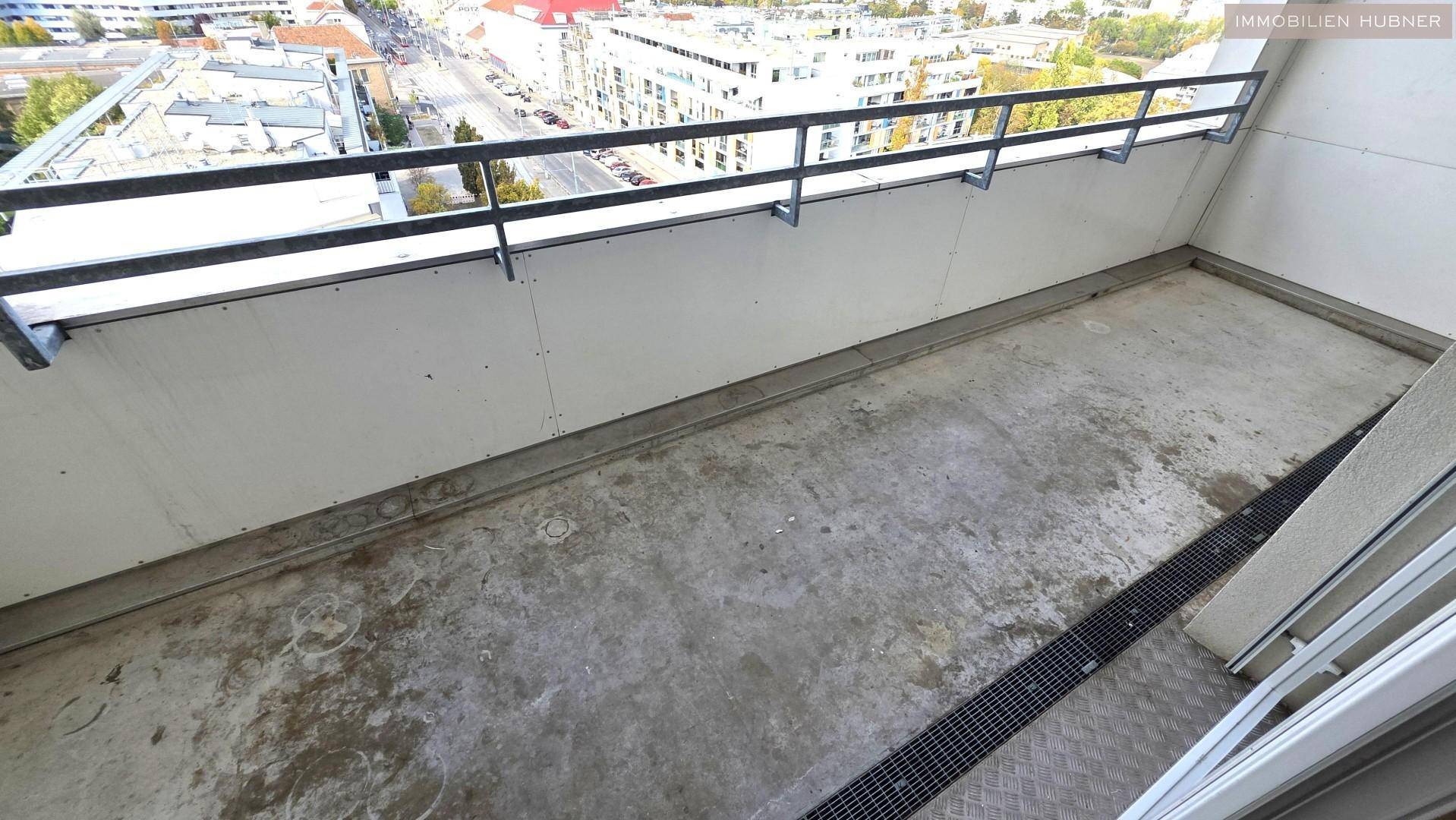 Unmöblierter Balkon mit Betonboden und Metallgeländer, bietet einen weiten Blick über die Stadt.