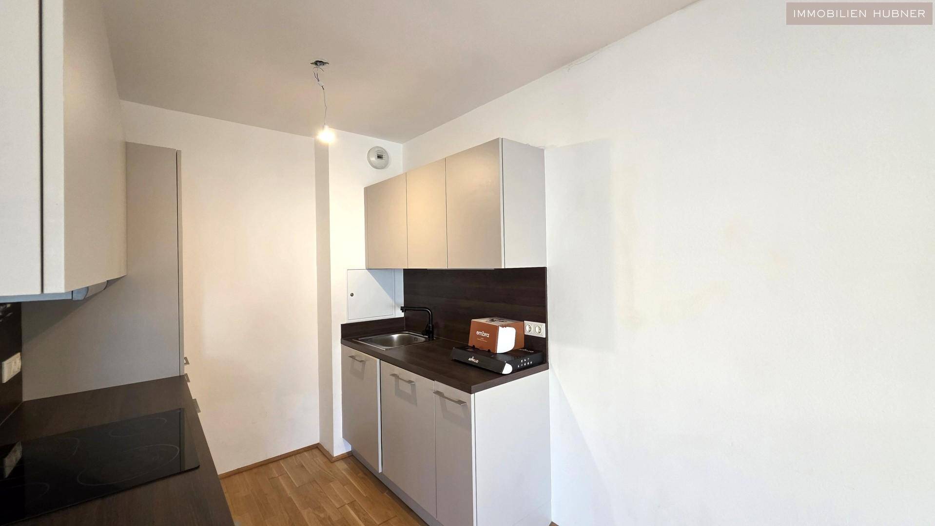 Kompakte Kochnische mit Spüle, Kochfeld und Stauraum in einem modernen Design.