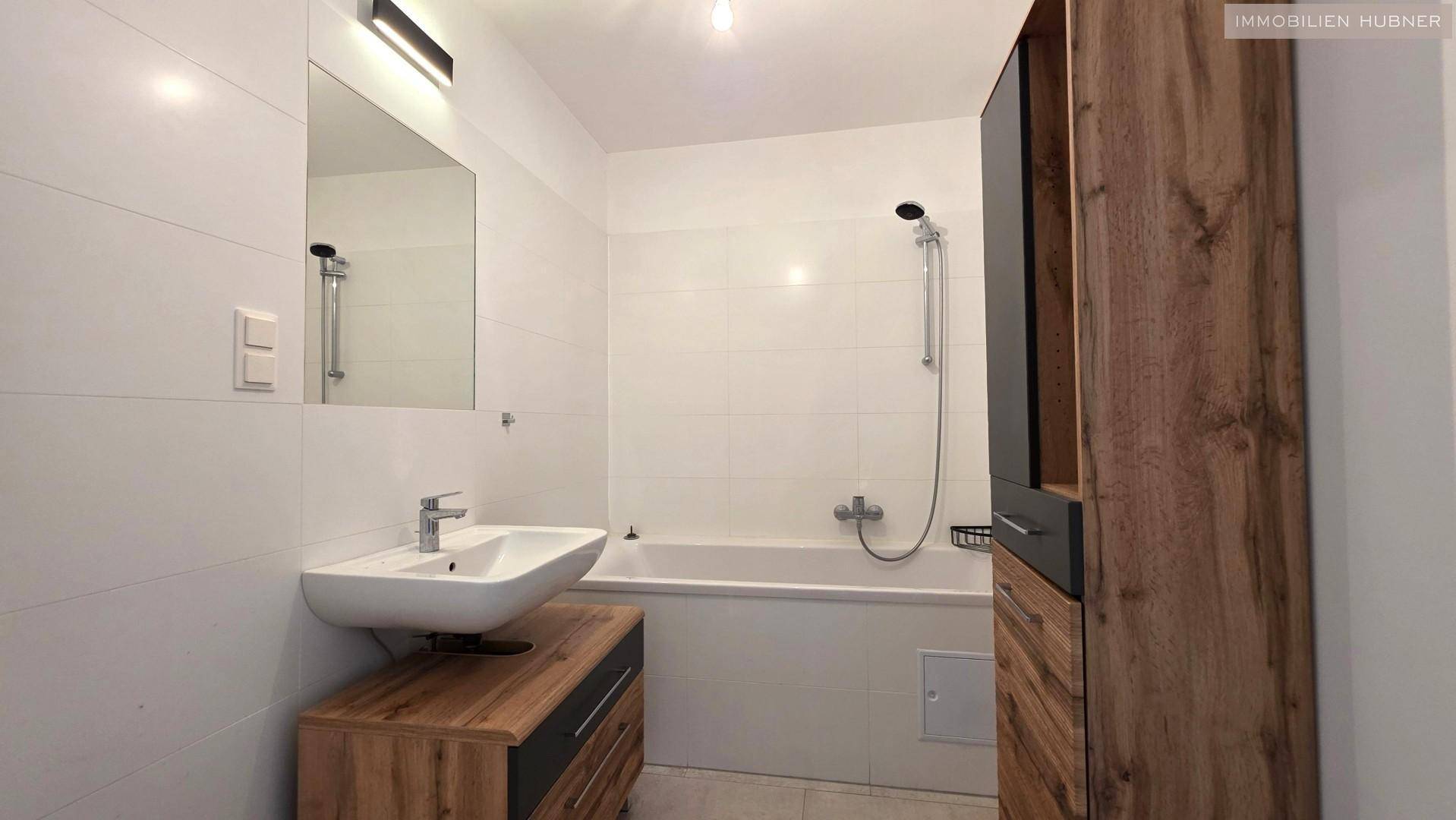 Modernes Badezimmer mit Badewanne, Dusche und einem stilvollen Holzwaschtischunterschrank.