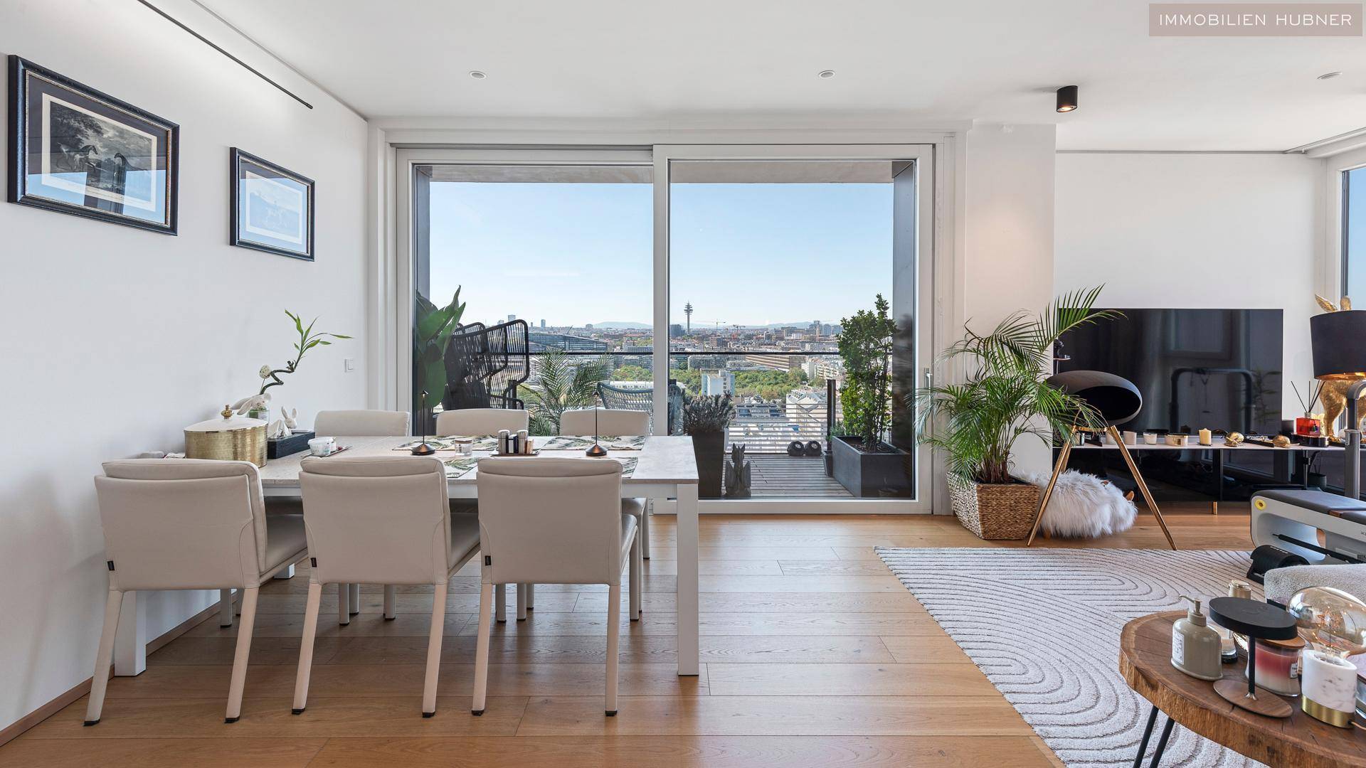 Geräumiger Wohn-Essbereich mit Holzboden, elegantem Esstisch und Zugang zum Balkon.