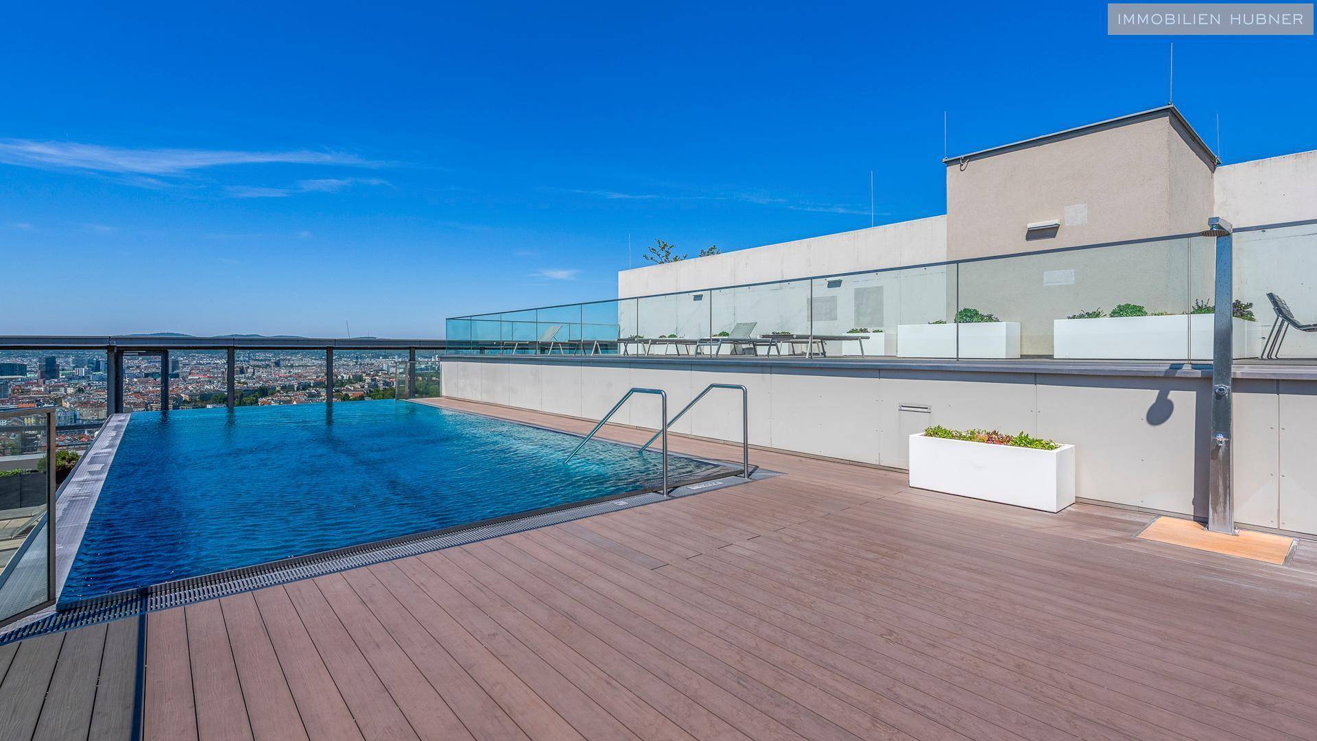 Dachterrasse mit Infinity-Pool, Liegebereich und weitem Blick über die Stadt.