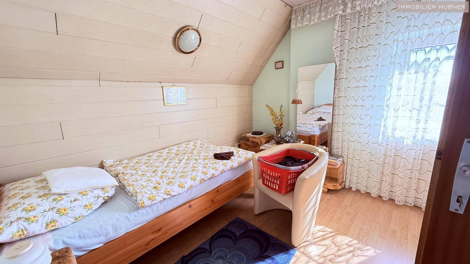 Helles Schlafzimmer im Dachgeschoss mit Einzelbett, Holzverkleidung und Dachschräge.