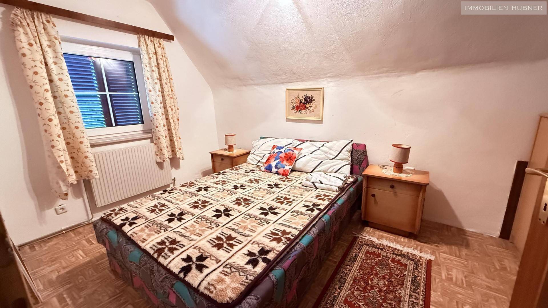 Schlafzimmer im Dachgeschoss mit Doppelbett, Fenster und Dachschräge.