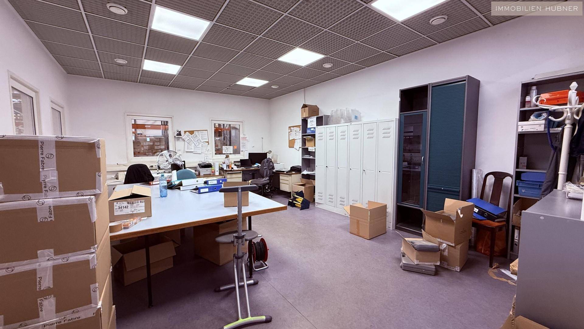 Großes Büro mit mehreren Arbeitsplätzen, Aktenschränken und abgehängter Decke.