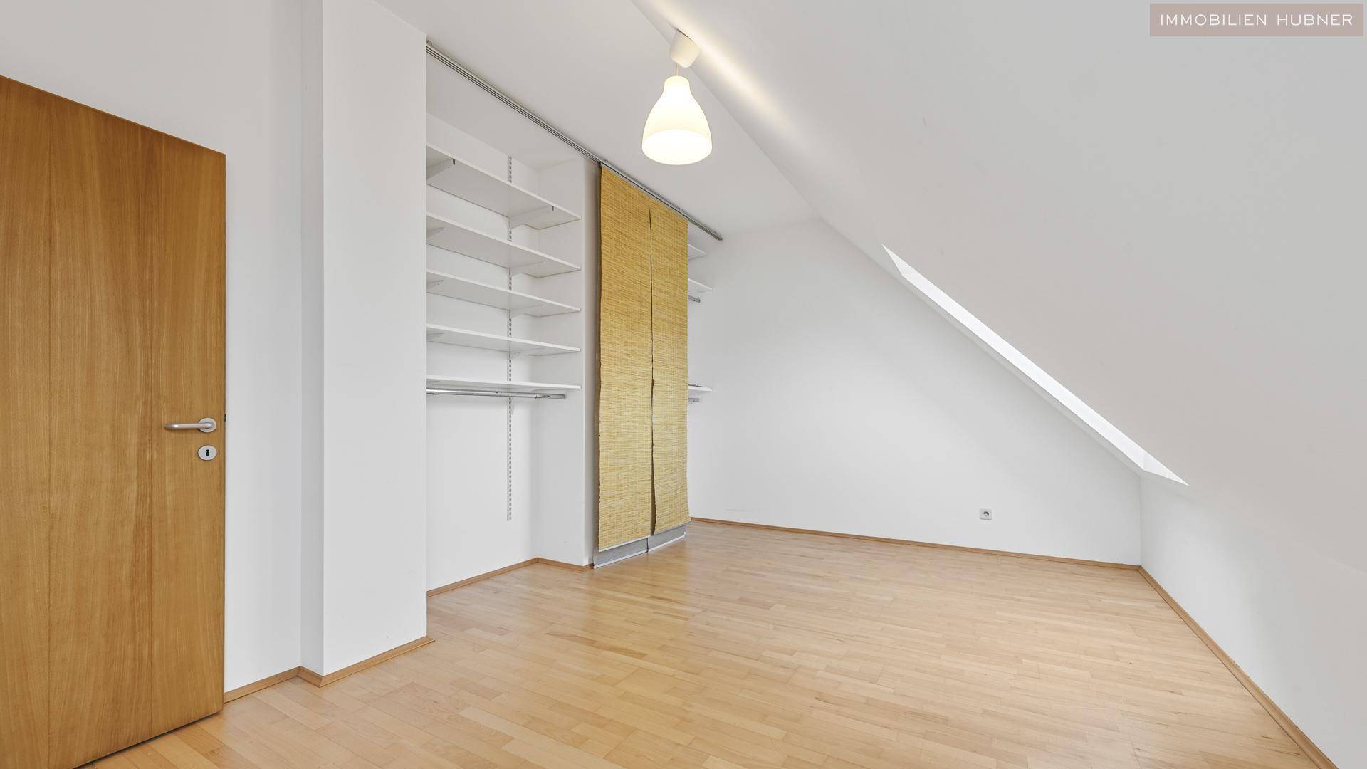 Schlafzimmer mit Holzboden, Dachschräge und integriertem Schranksystem für viel Stauraum.