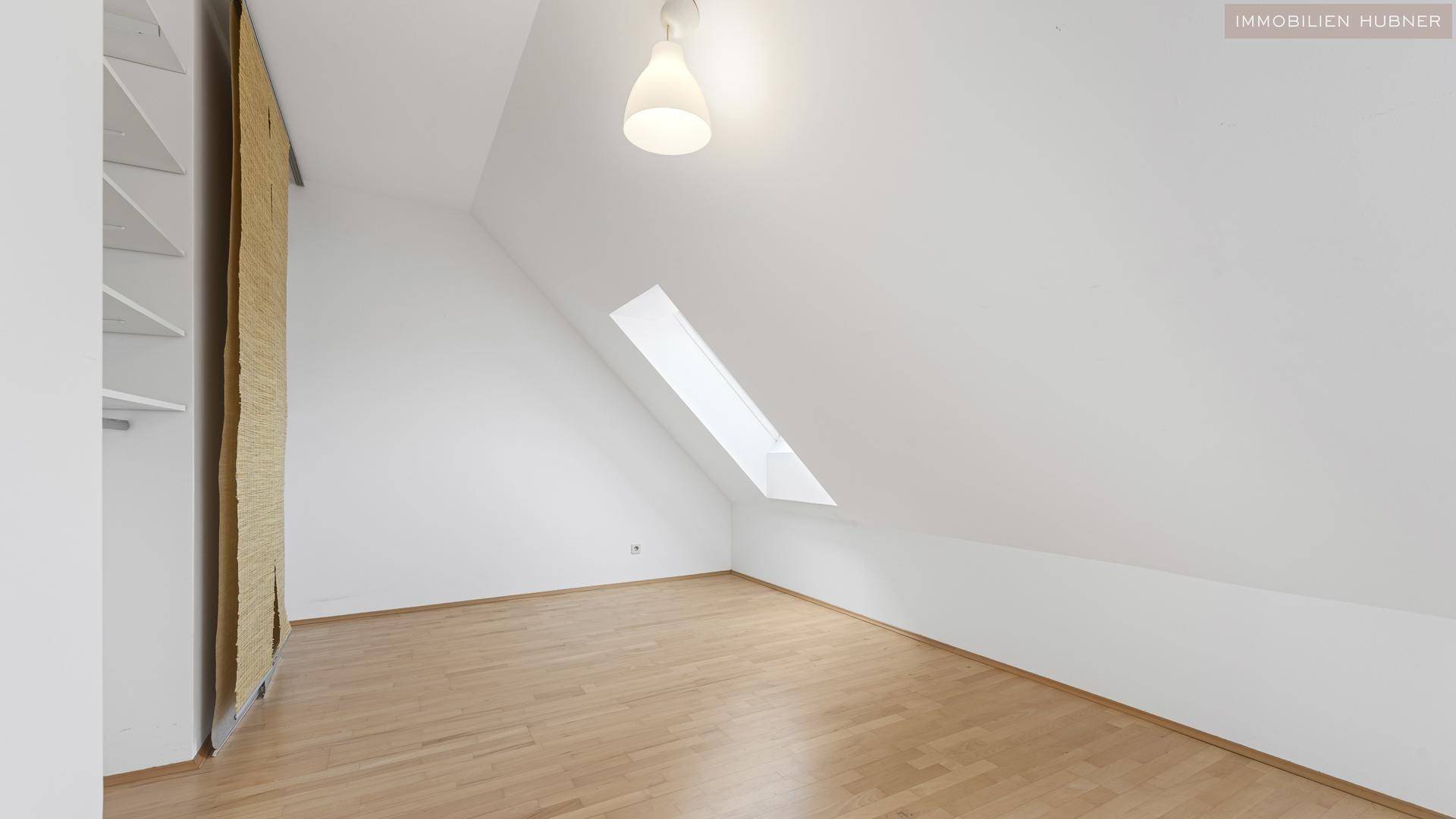Helles Schlafzimmer mit Holzboden, Dachschräge und Dachfenster, ideal für ein ruhiges Ambiente.