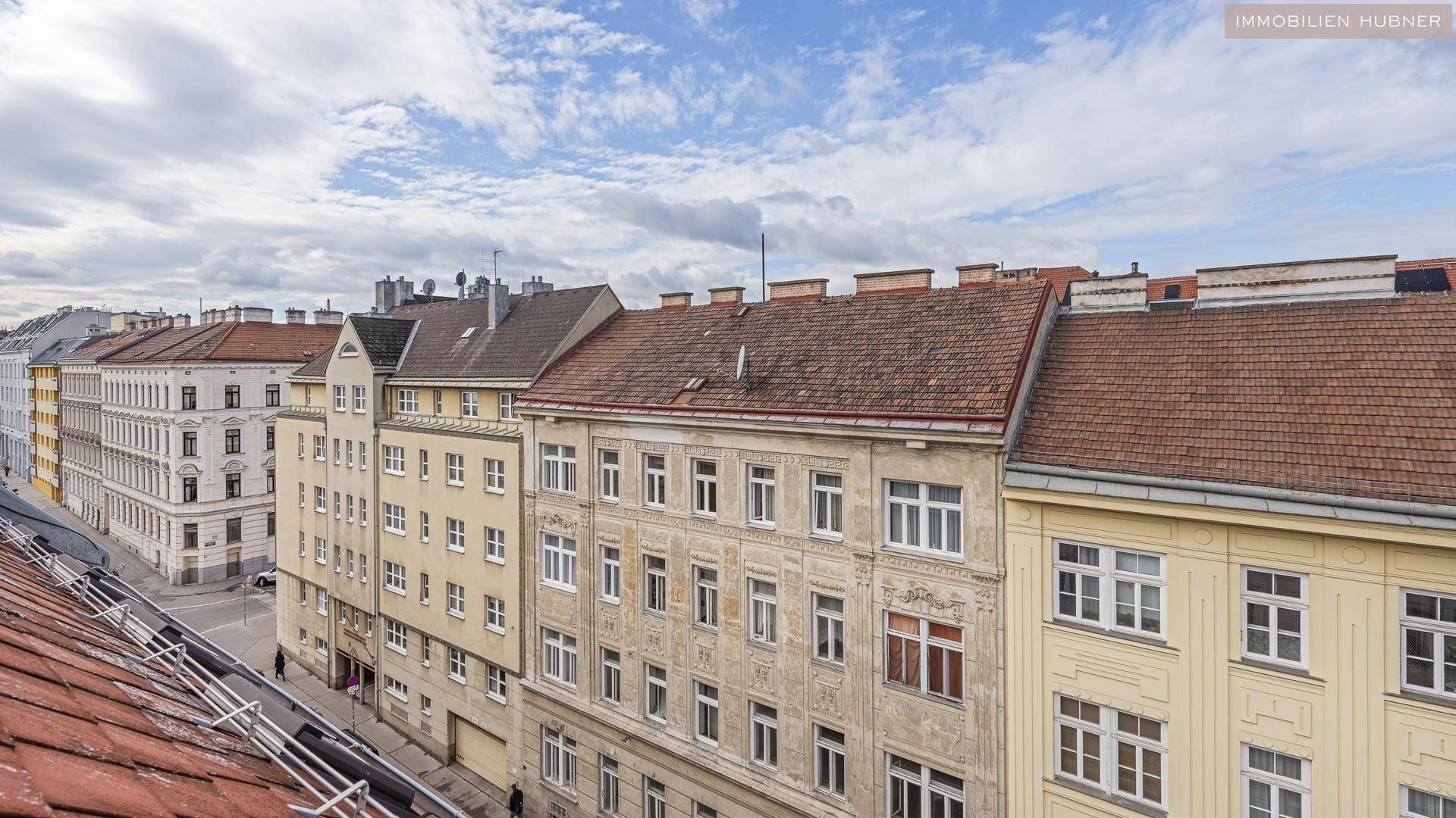 Weitblick über die städtische Bebauung mit verschiedenen Dächern und Fassaden unter einem blauen Himmel.