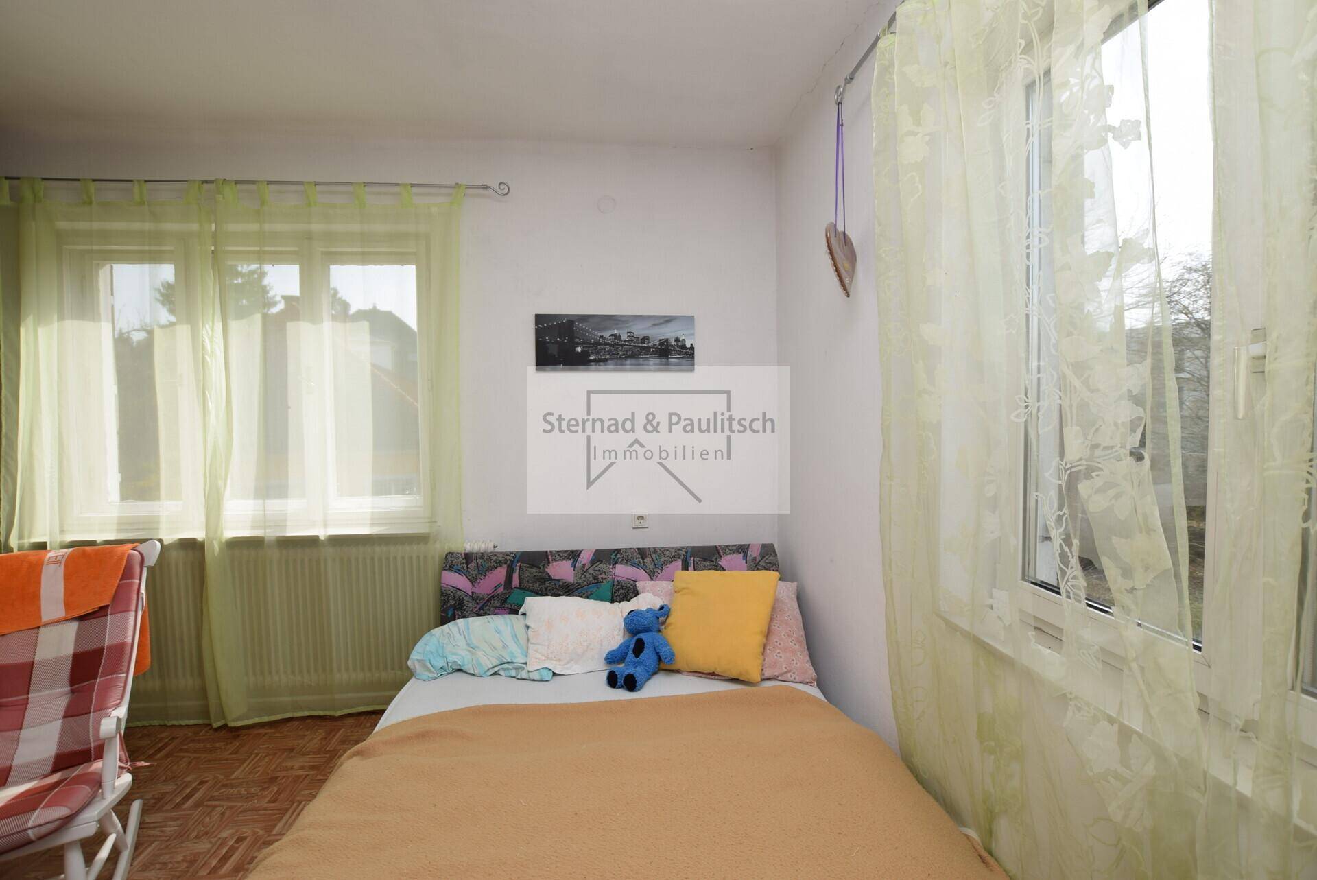 Helles Schlafzimmer mit zwei Fenstern und einem Einzelbett.