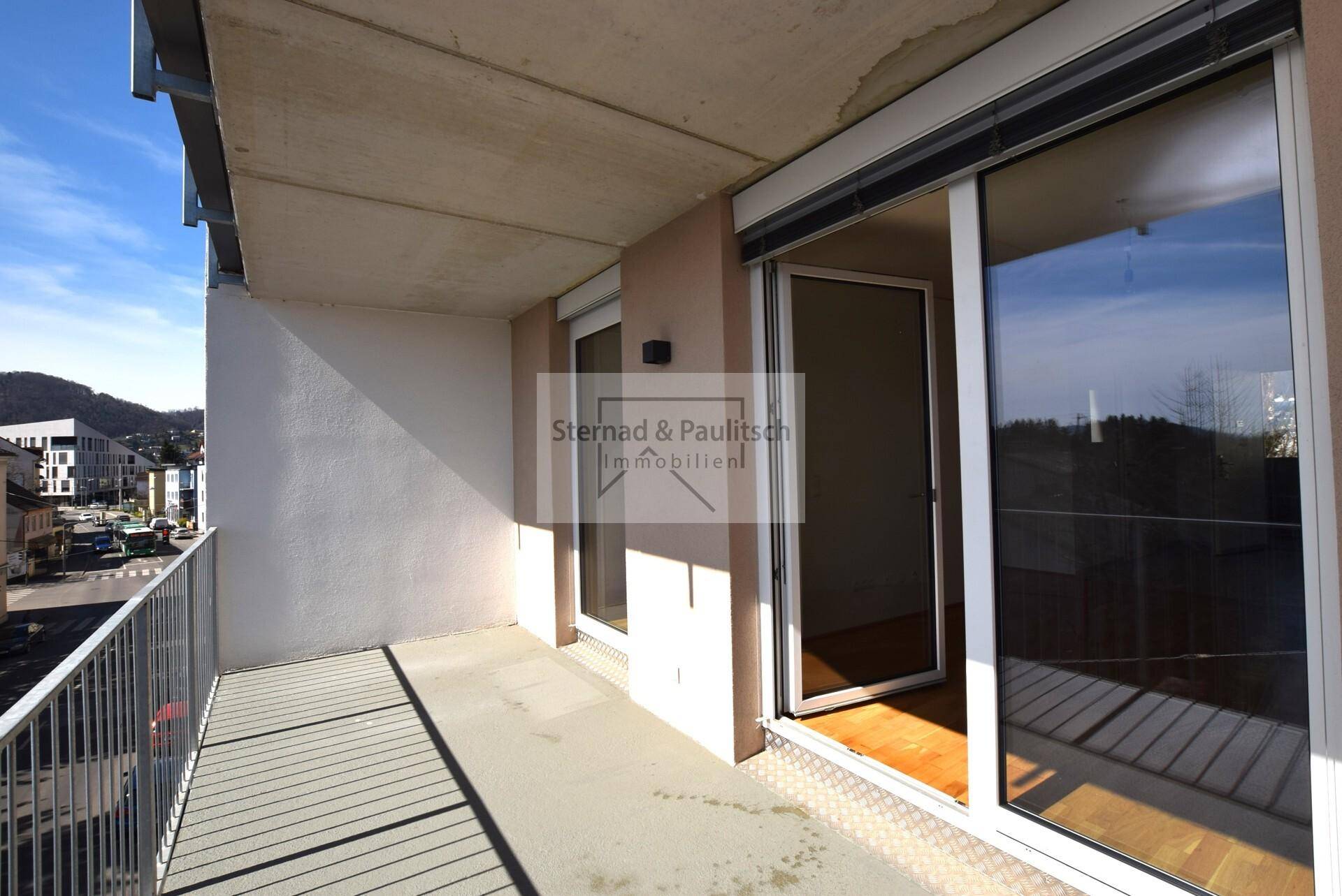 Breiter Balkon mit Metallgeländer und weitem Blick auf die Stadt und die umliegende Landschaft.