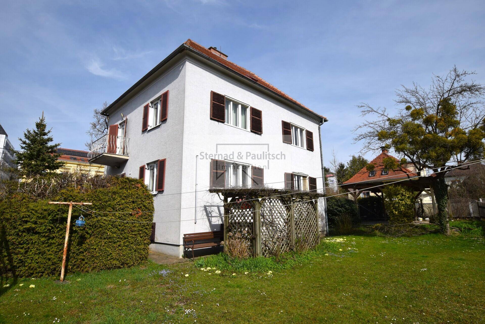 Seitenansicht des Hauses mit Garten und einem kleinen Balkon im Obergeschoss.