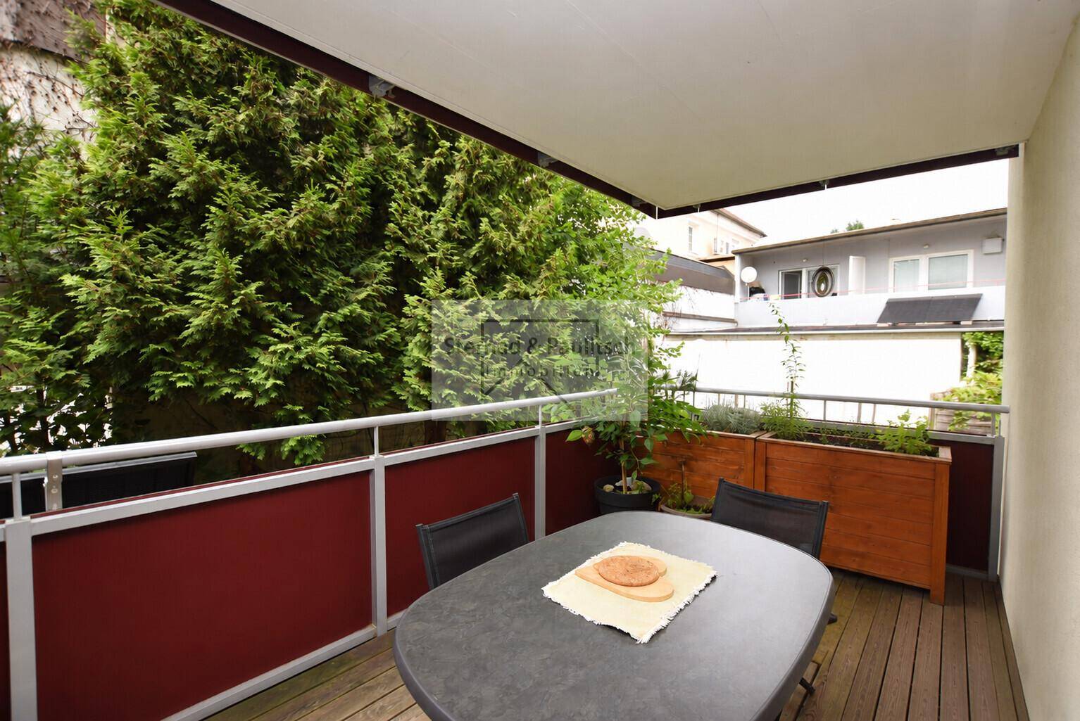 Gemütlicher Balkon mit Holzboden und Pflanzen, ideal für entspannte Stunden im Freien.