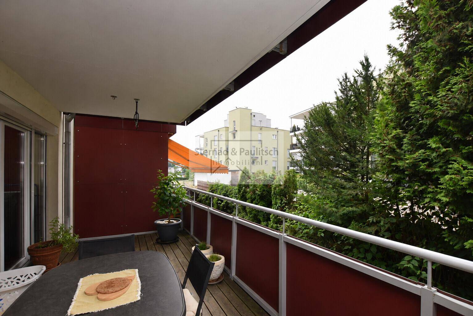 Geräumiger Balkon mit Holzboden und Markise, bietet einen schönen Blick ins Grüne und auf die Umgebung.