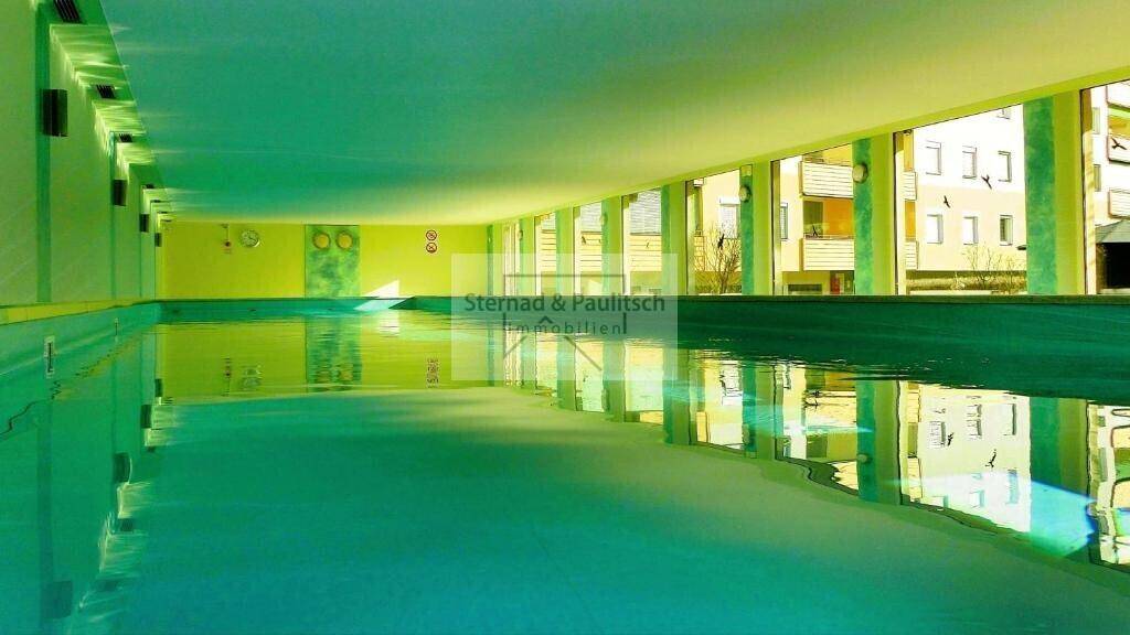 Großes Hallenbad mit türkisfarbenem Wasser und Blick auf die umliegenden Gebäude.