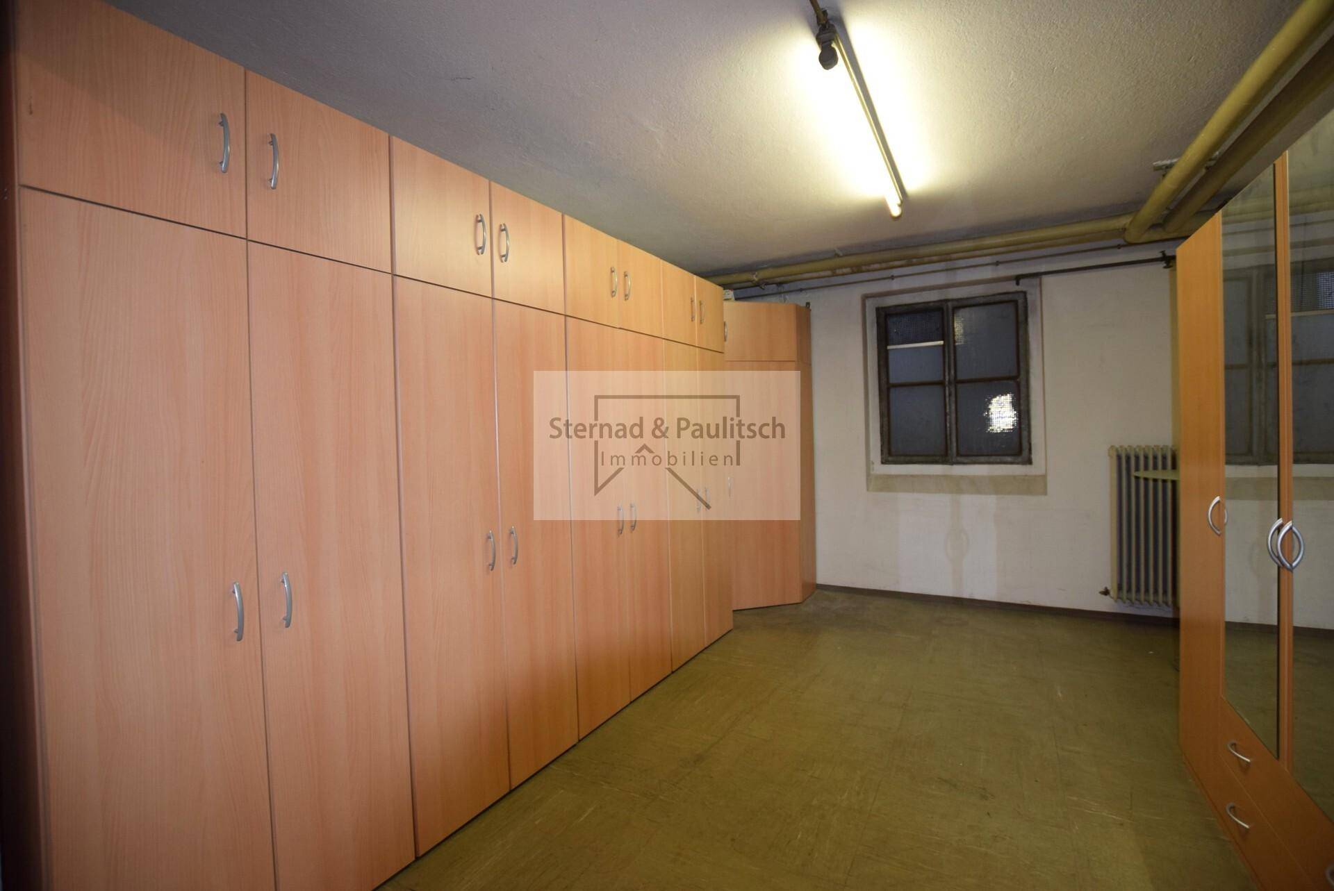 Praktischer Abstellraum im Keller mit vielen Einbauschränken und einem Fenster.