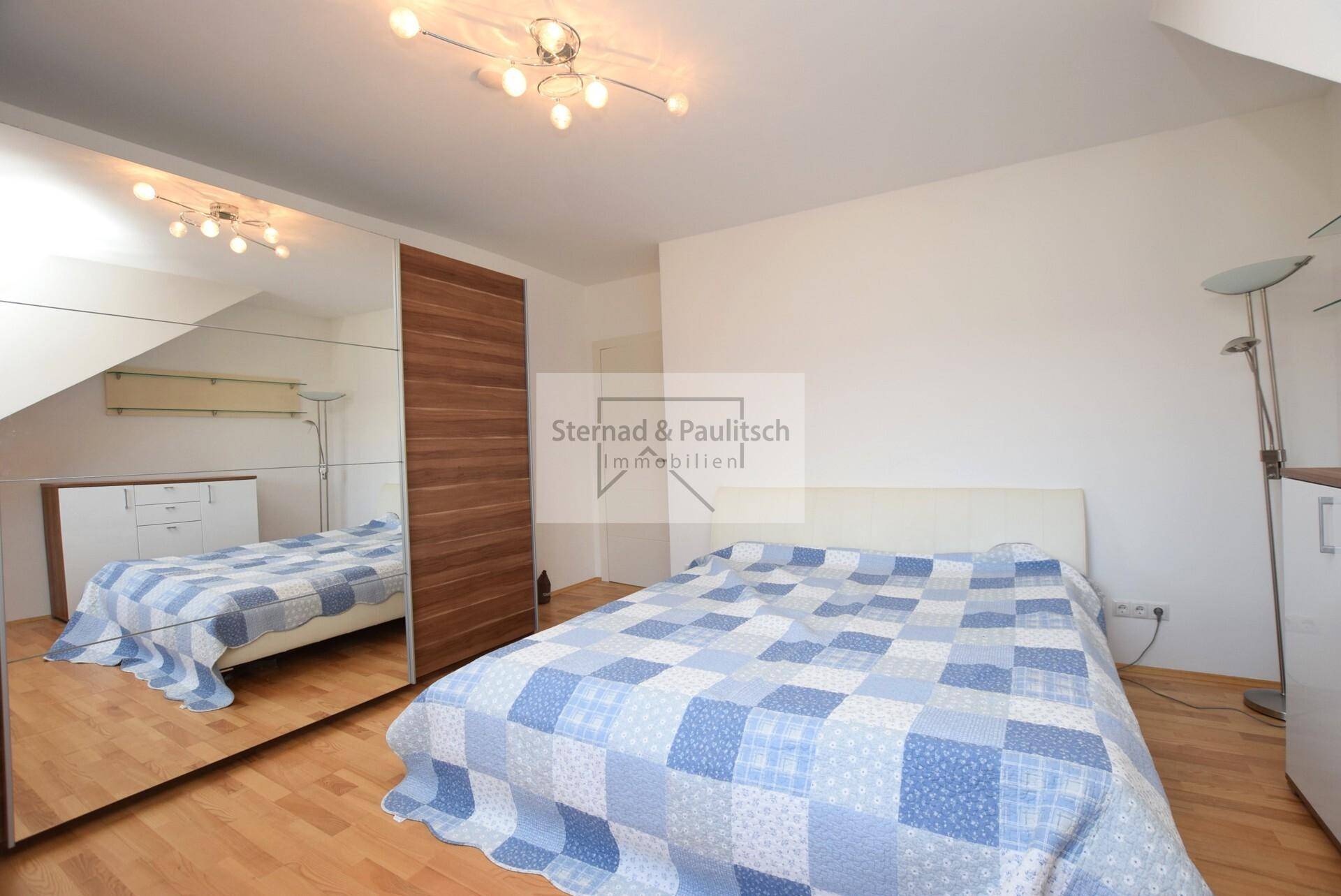 Schlafzimmer mit Holzboden, großem Spiegelschrank und gemütlichem Bett.