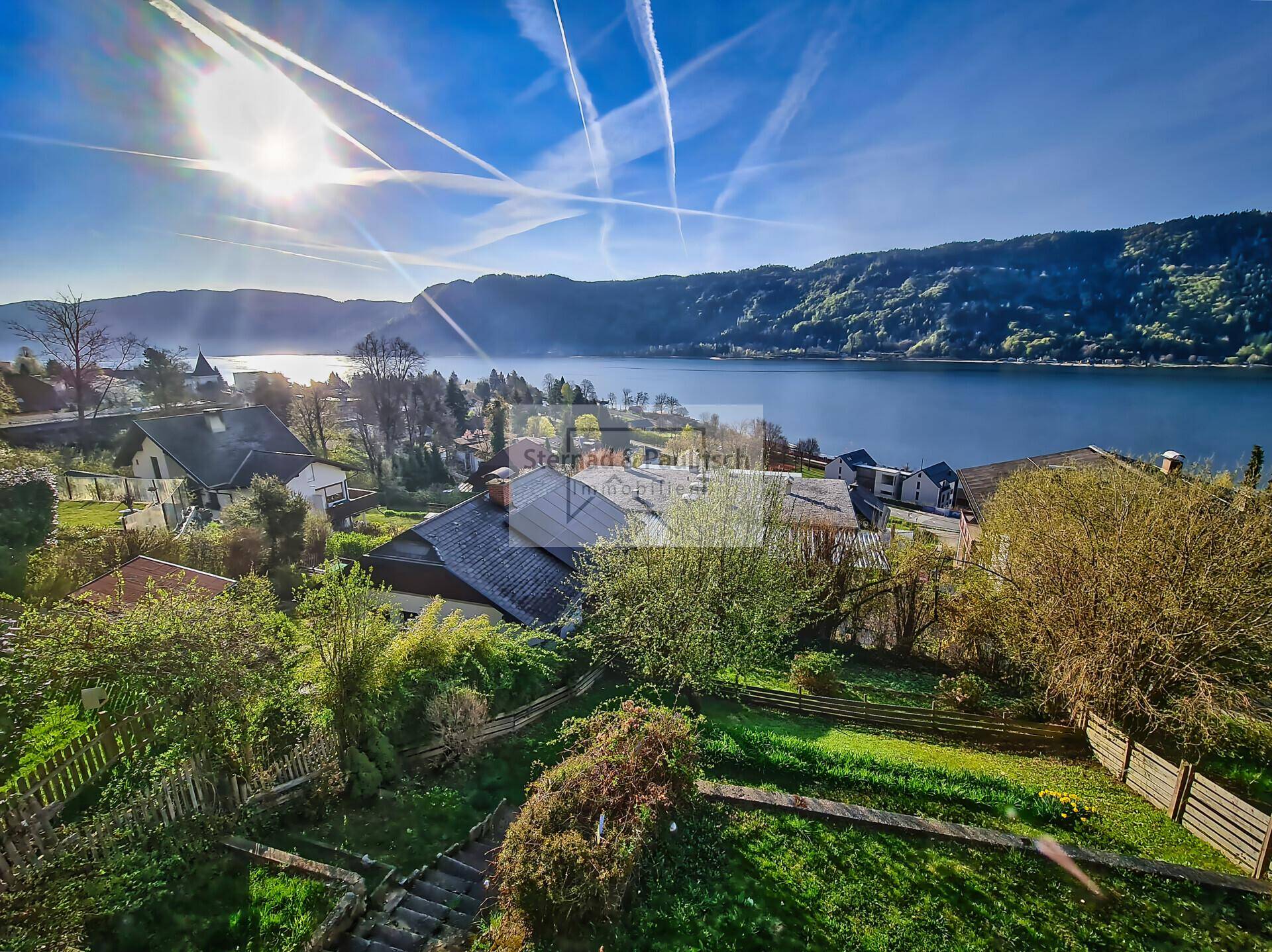 Sonniger Gartenbereich mit Blick auf den See und die umliegenden Berge.