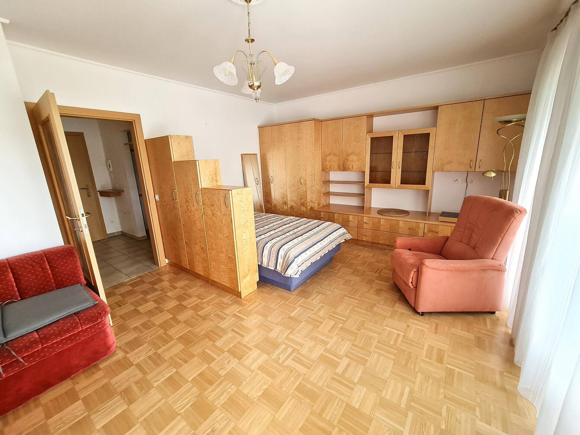 Gemütliches Schlafzimmer mit Parkettboden, Einbauschränken aus Holz und einem bequemen Sessel.