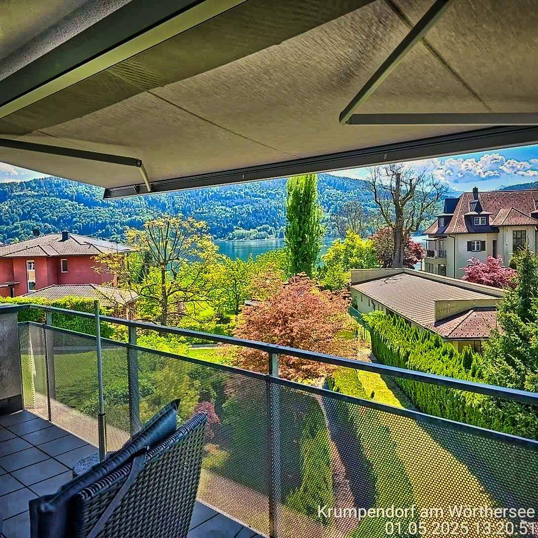 Geräumiger Balkon mit Sitzgelegenheiten und weitem Blick auf den Wörthersee und die umliegende Natur.