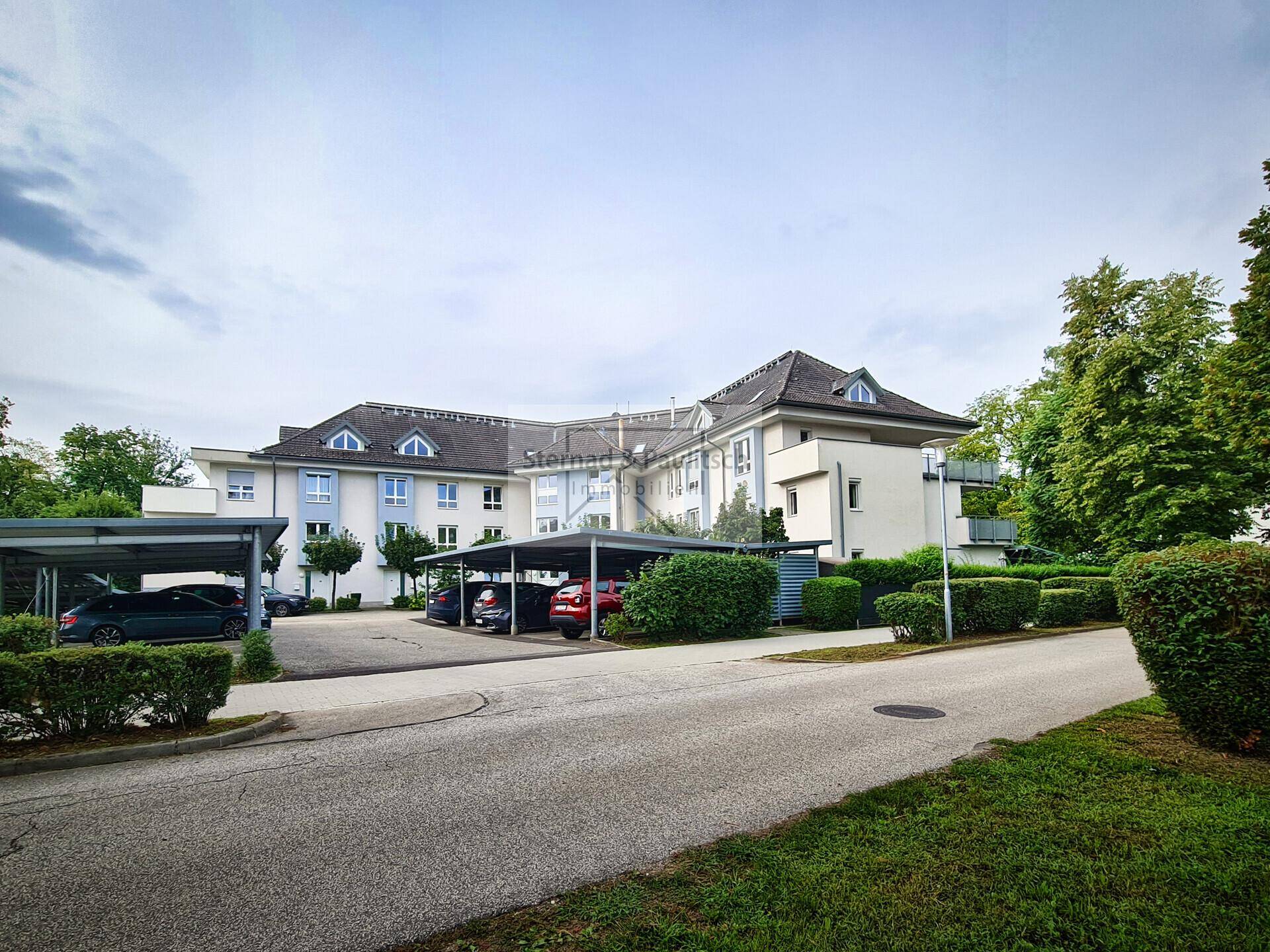Mehrstöckiges Wohngebäude mit mehreren Carports und gepflegter Außenanlage.