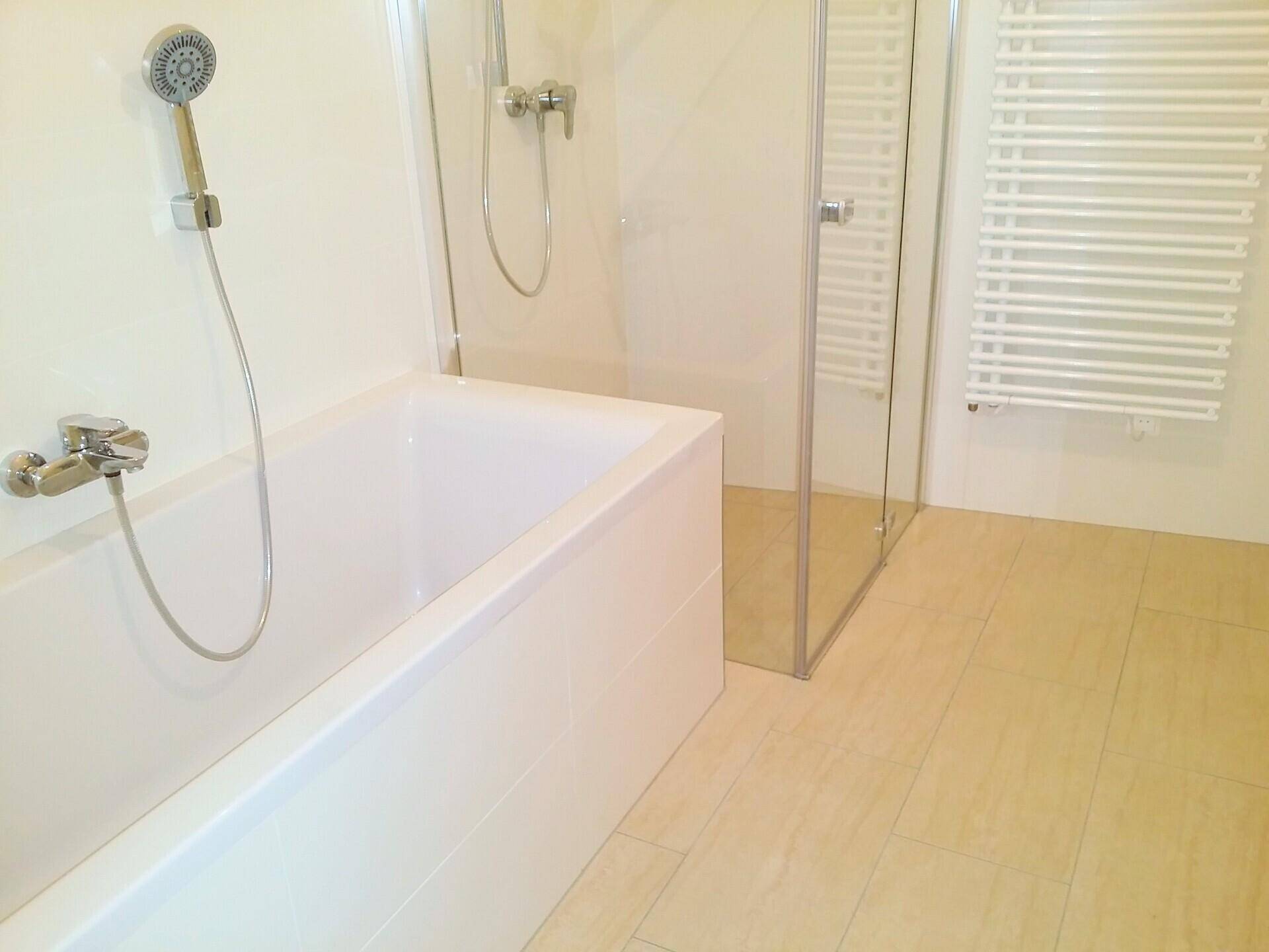 Modernes Badezimmer mit Badewanne, Glasdusche und praktischem Handtuchheizkörper.