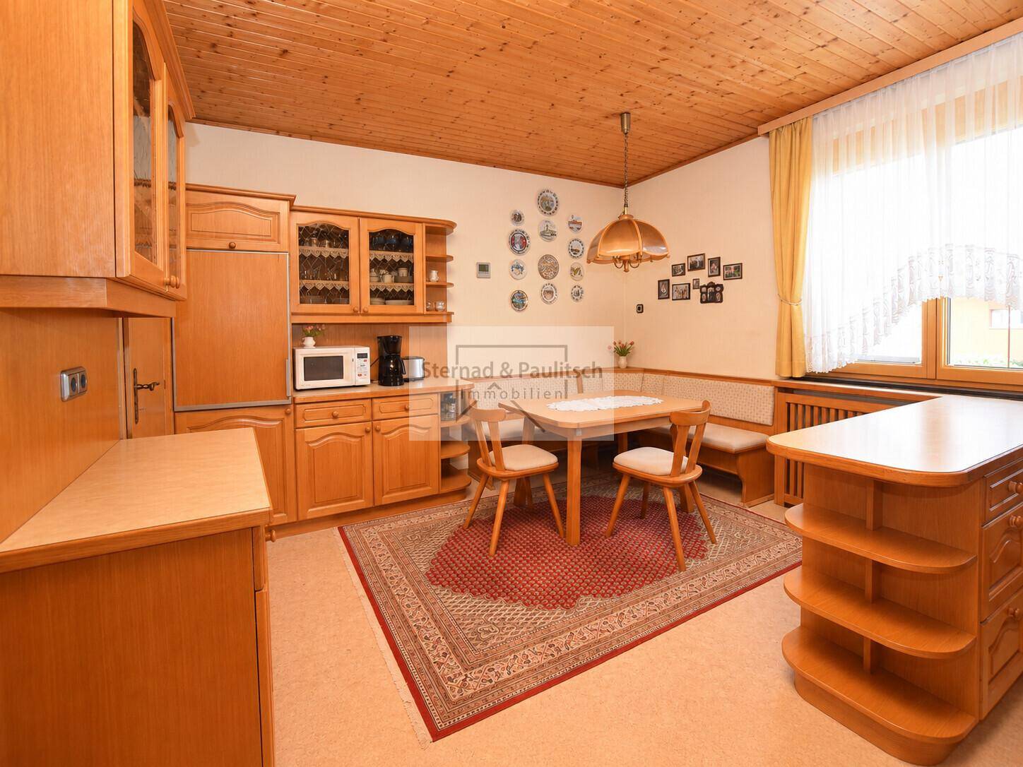 Geräumige Wohnküche mit Essecke, Holztisch und traditionellen Holzschränken.