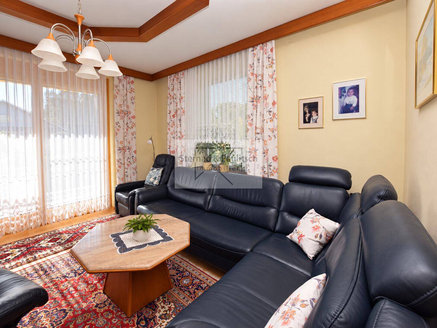 Detailansicht des Wohnzimmers mit Ledersofa, Couchtisch und Blick auf die Fensterfront.