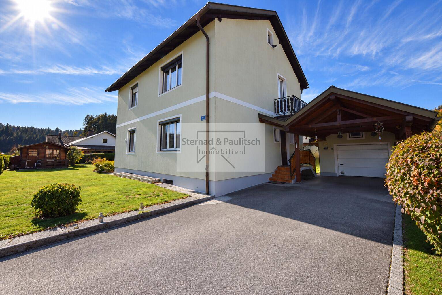 Ansicht des Einfamilienhauses mit Zufahrt, Carport und gepflegter Fassade an einem sonnigen Tag.