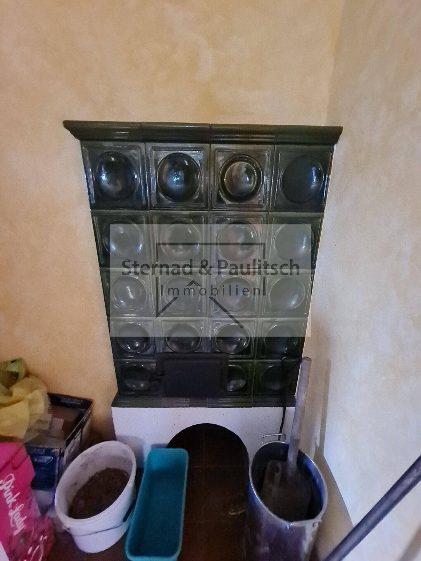 Traditioneller Kachelofen mit dunklen Glaselementen, als Heizquelle im Wohnbereich.