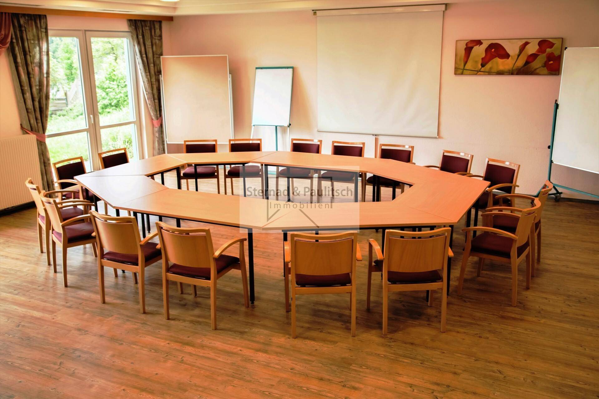 Konferenzraum mit achteckigem Tisch und Stühlen, bereit für Besprechungen.