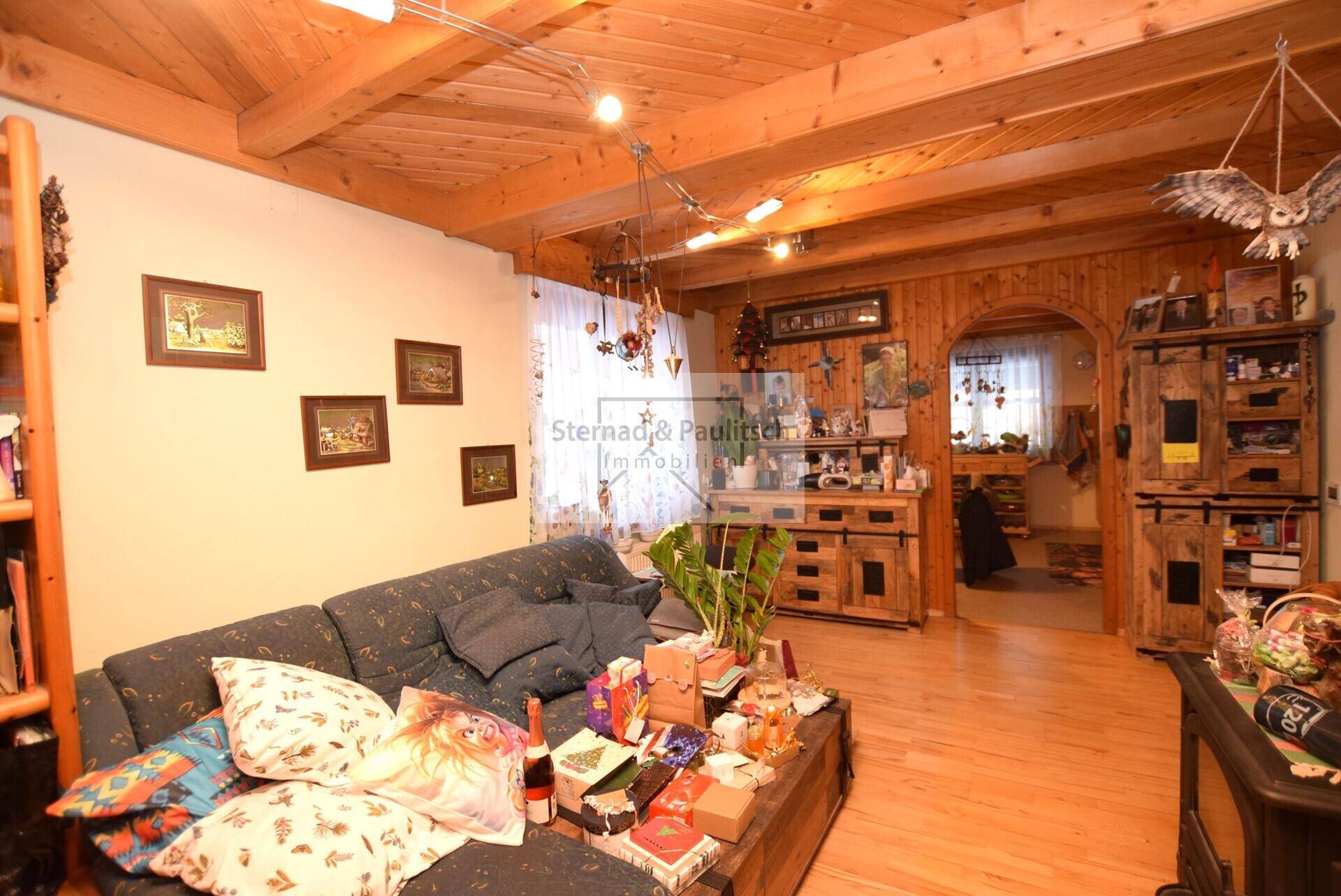 Rustikales Wohnzimmer mit Holzbalkendecke, bequemer Couch und traditionellen Dekorationen.