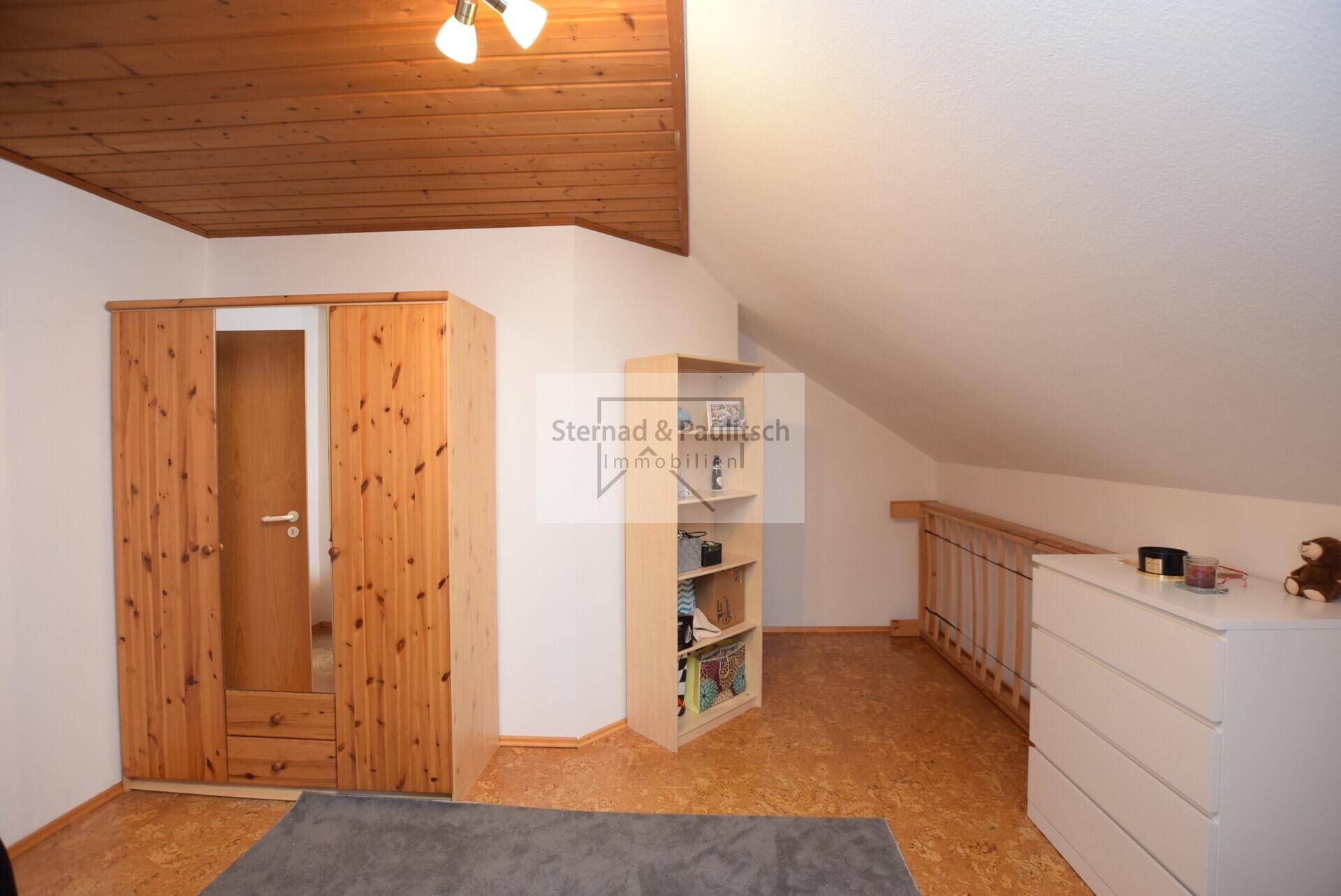 Schlafzimmer im Dachgeschoss mit Dachschräge, Kleiderschrank und Korkboden.