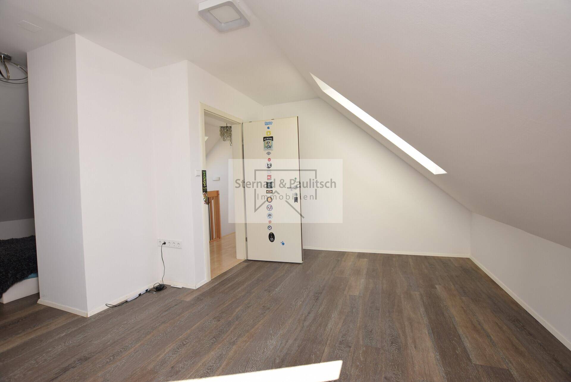 Geräumiger Dachbodenraum mit Laminatboden und schrägen Wänden.