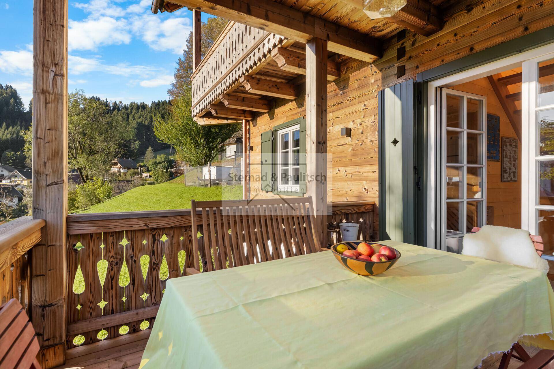 Geräumiger Holzbalkon mit Esstisch und Stühlen, bietet einen weiten Blick ins Grüne.