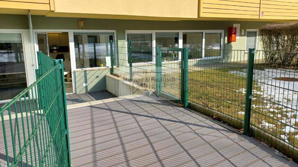 Zugangsbereich zur Wohnung im Erdgeschoss mit kleiner Terrasse und Zaun.