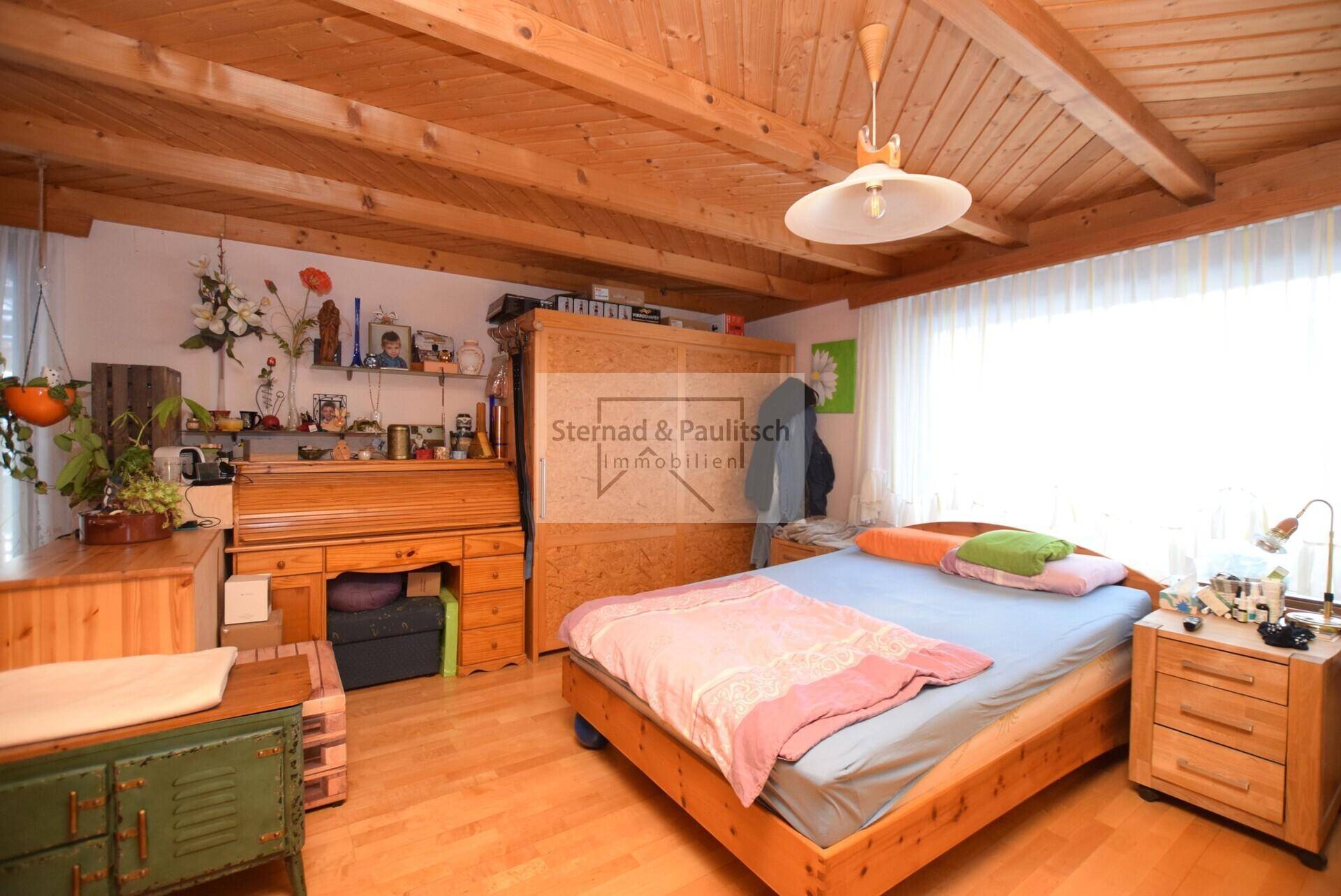 Schlafzimmer mit Holzbalkendecke, Holzboden und traditionellen Holzmöbeln, hell und einladend.