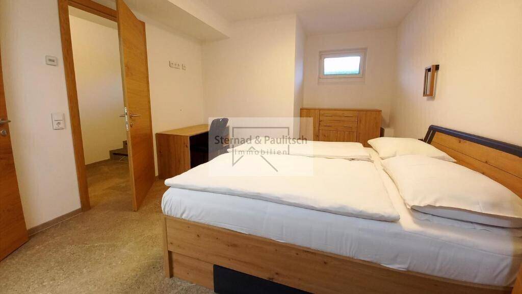 Helles Schlafzimmer mit Holzbett und Blick auf den Flur und weitere Räume.