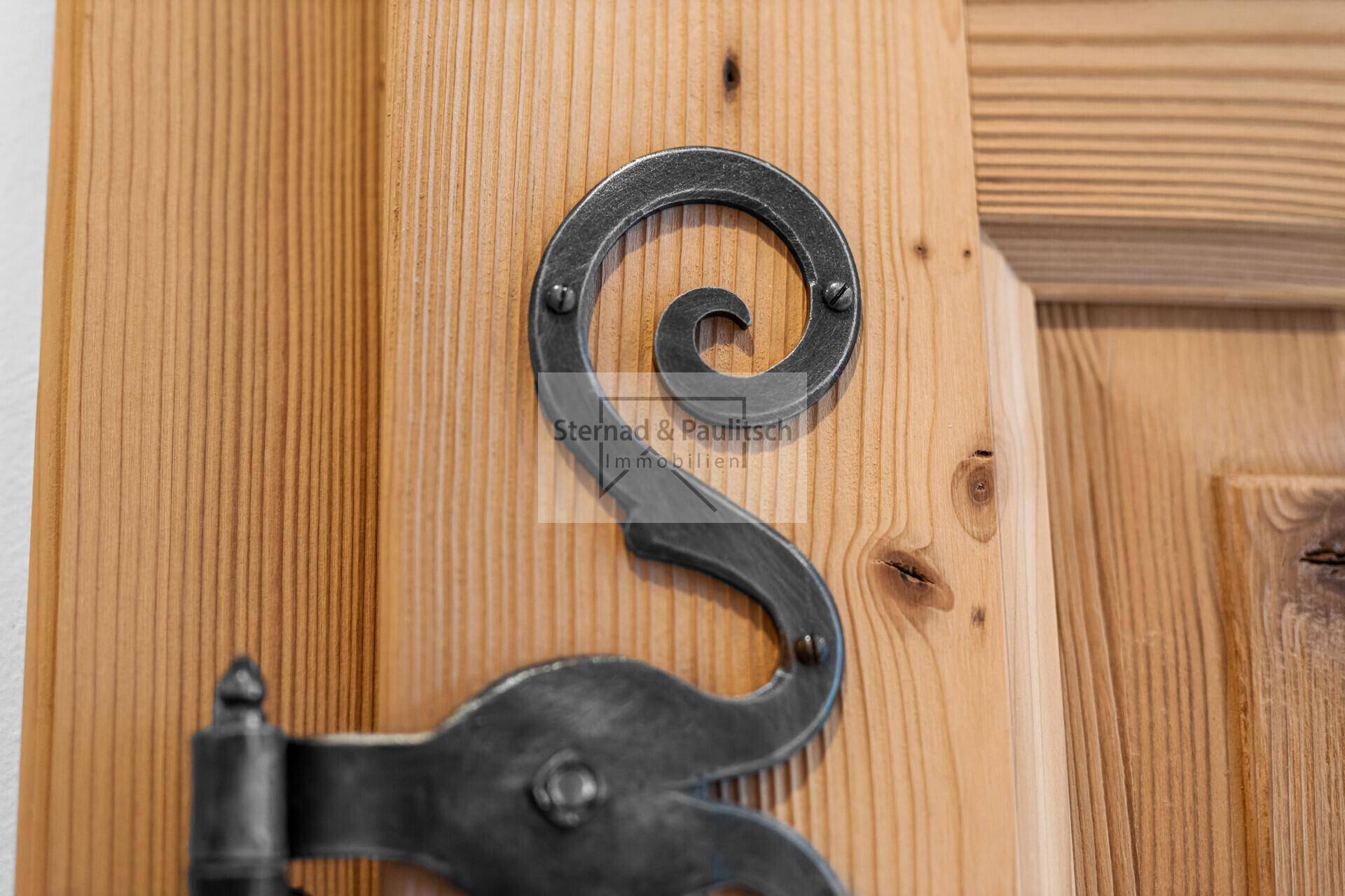 Detailaufnahme eines traditionellen schmiedeeisernen Beschlags an einer Holztür.
