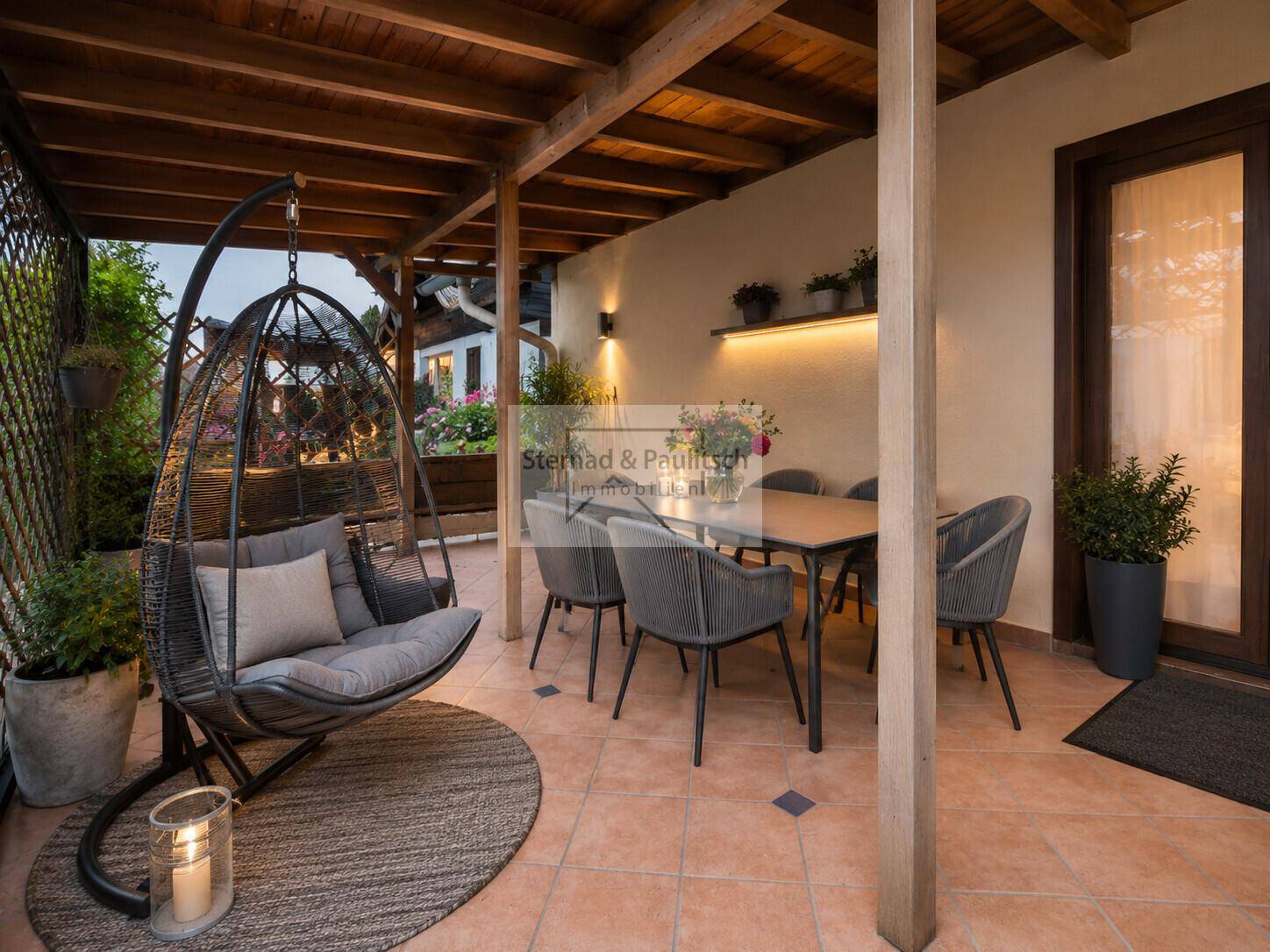 Modernisierte überdachte Terrasse mit stilvollen Outdoor-Möbeln und gemütlichem Hängesessel.