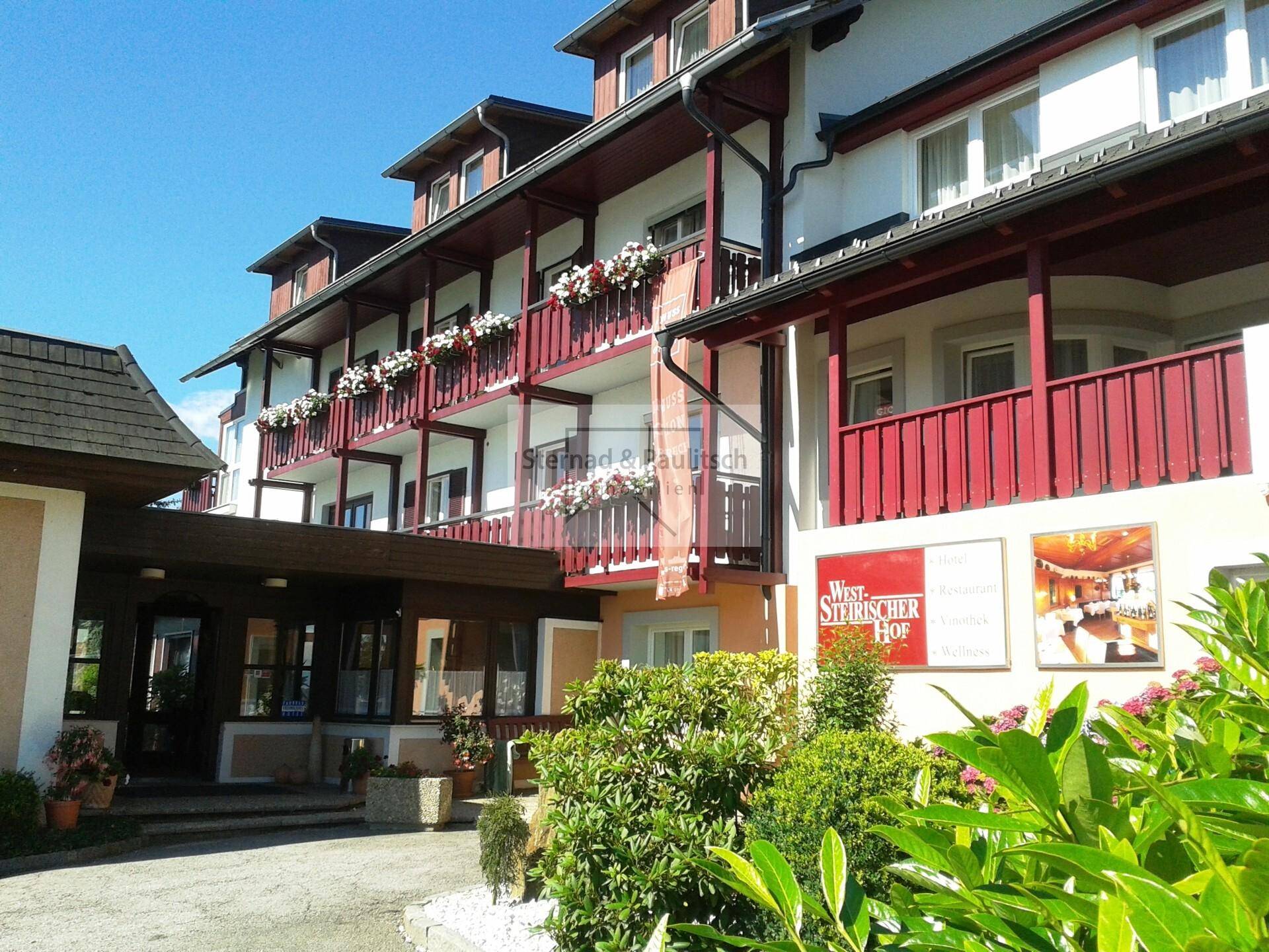 Hotelgebäude mit Balkonen, Blumenkästen und einem einladenden Eingangsbereich unter blauem Himmel.