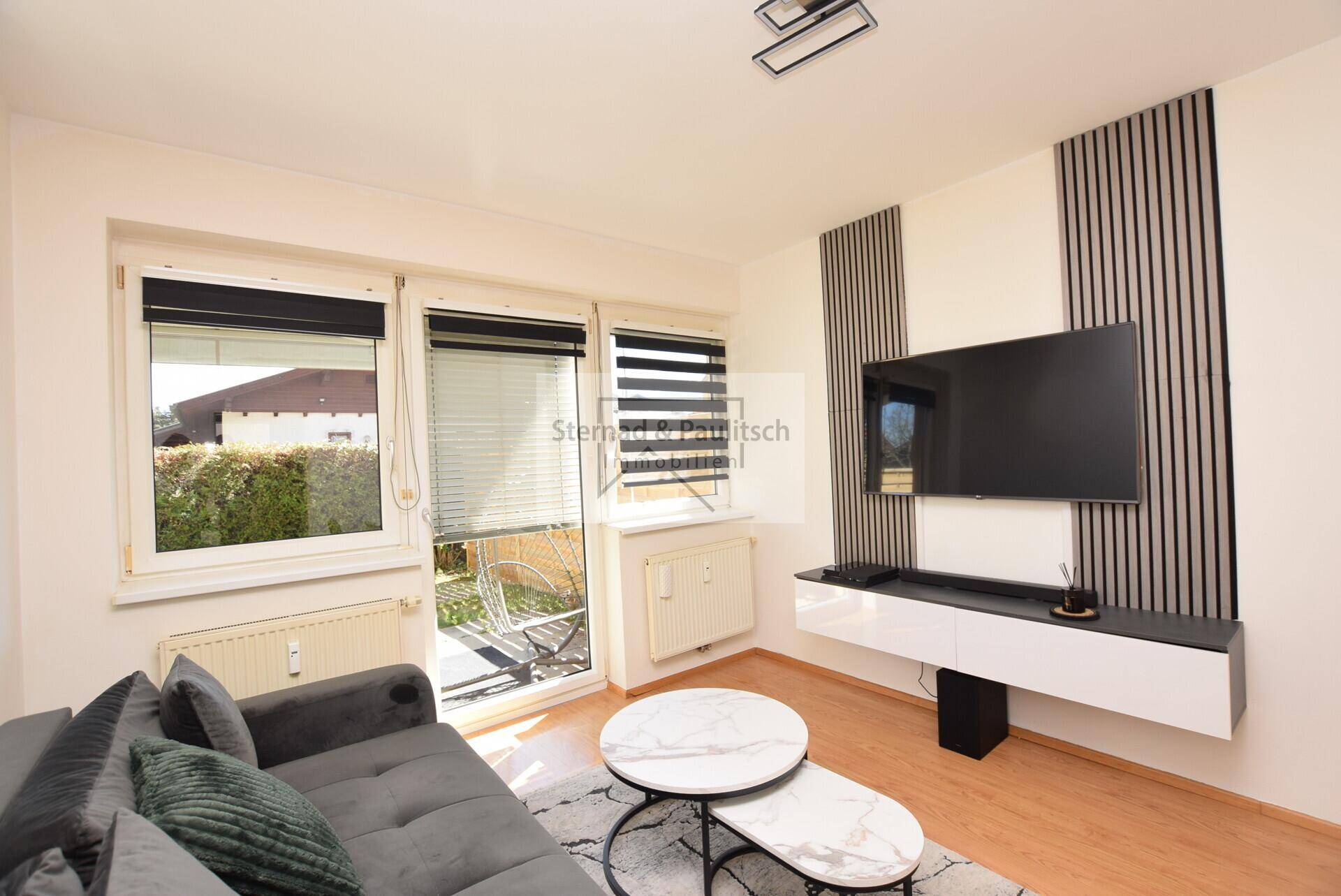 Helles Wohnzimmer mit modernem Sofa, stilvollen Couchtischen und direktem Zugang zur Terrasse.
