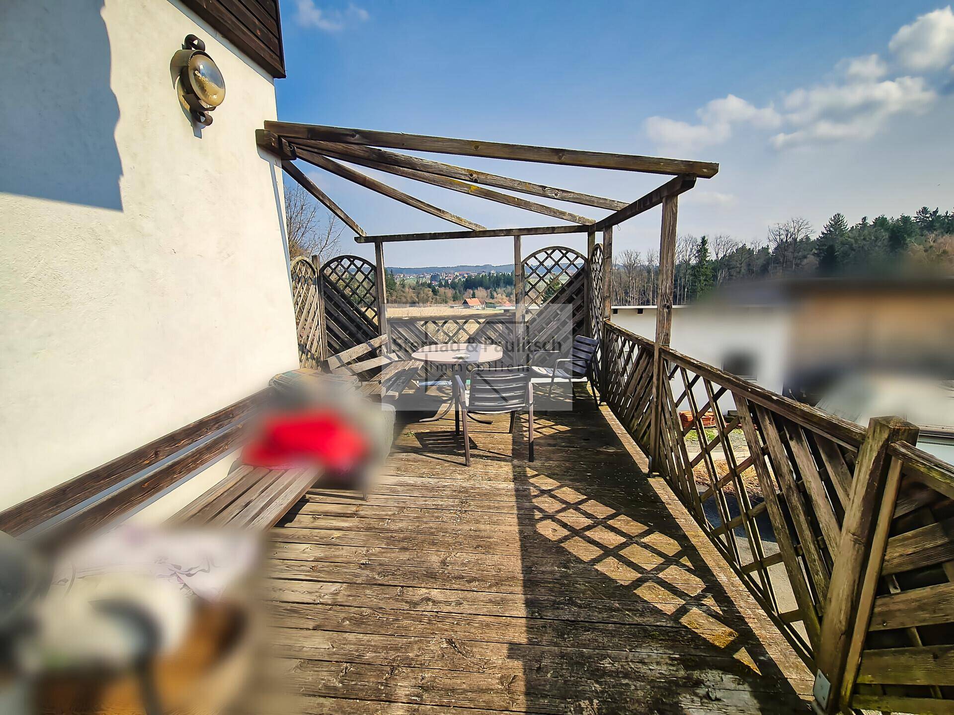 Rustikaler Holzbalkon mit Sitzgelegenheiten und weitem Blick in die Landschaft.