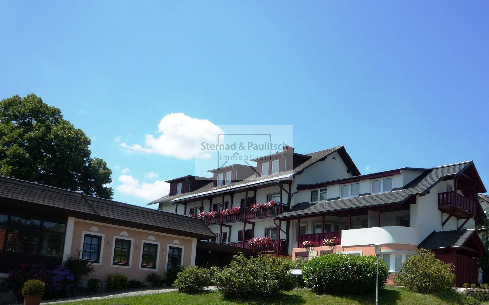 Weitläufige Ansicht des Gebäudekomplexes mit gepflegter Außenanlage unter blauem Himmel.