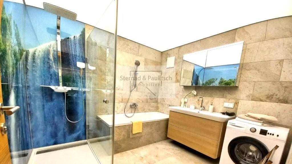 Geräumiges Badezimmer mit Dusche, Badewanne, Waschbecken und Waschmaschine, praktisch und hell.