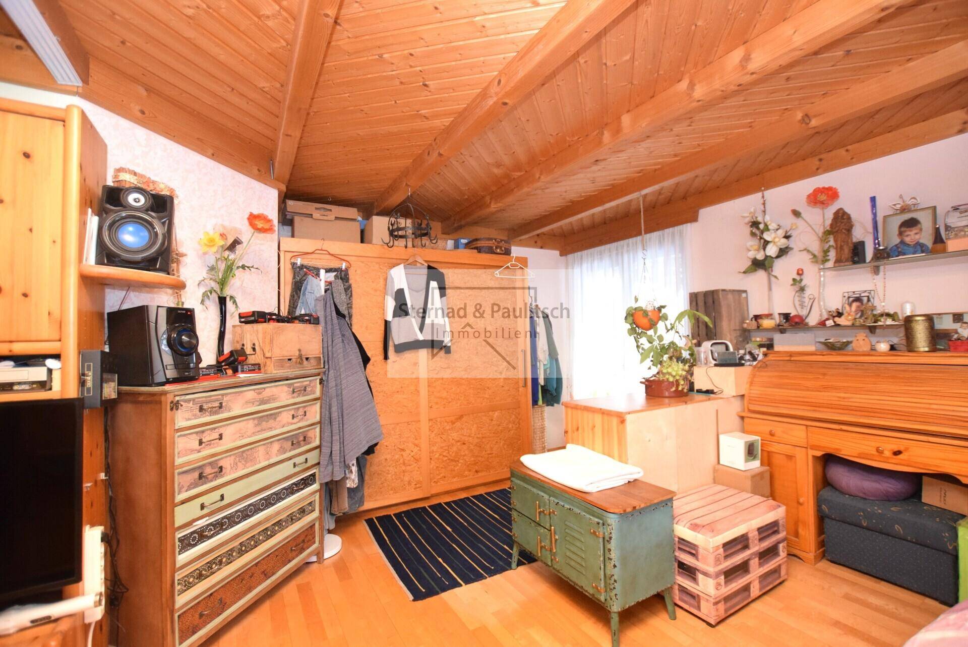 Geräumiges Schlafzimmer mit Holzbalkendecke, Holzboden und viel Stauraum in Holzmöbeln.