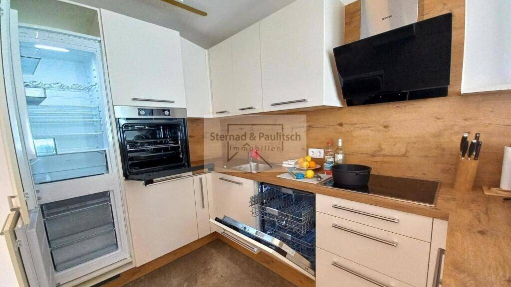 Voll ausgestattete Küche mit hellen Schränken, Kühlschrank und Geschirrspüler, bereit zum Kochen.