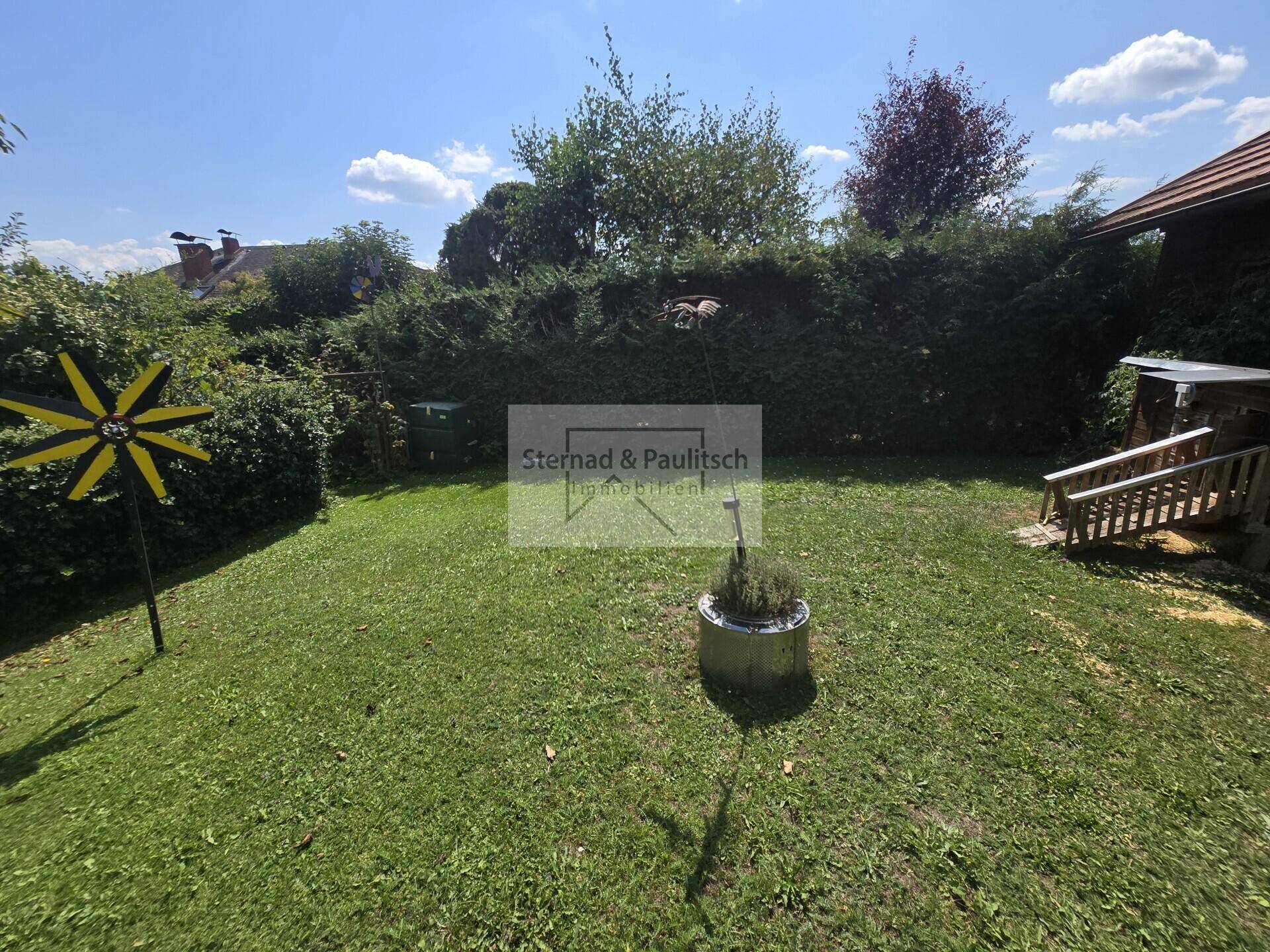 Gepflegter Garten mit Rasenfläche und hoher Hecke, ideal für Entspannung im Freien.