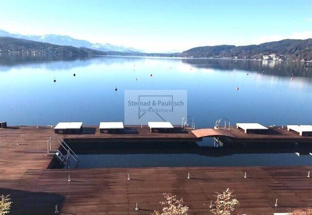 Weitläufige Holzterrasse mit integrierten Wasserbecken und direktem Zugang zum See mit Bergblick.