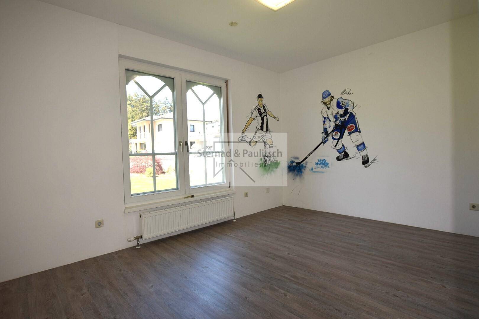 Kinderzimmer mit Holzboden, großem Fenster und Wandmalerei, ideal für junge Bewohner.