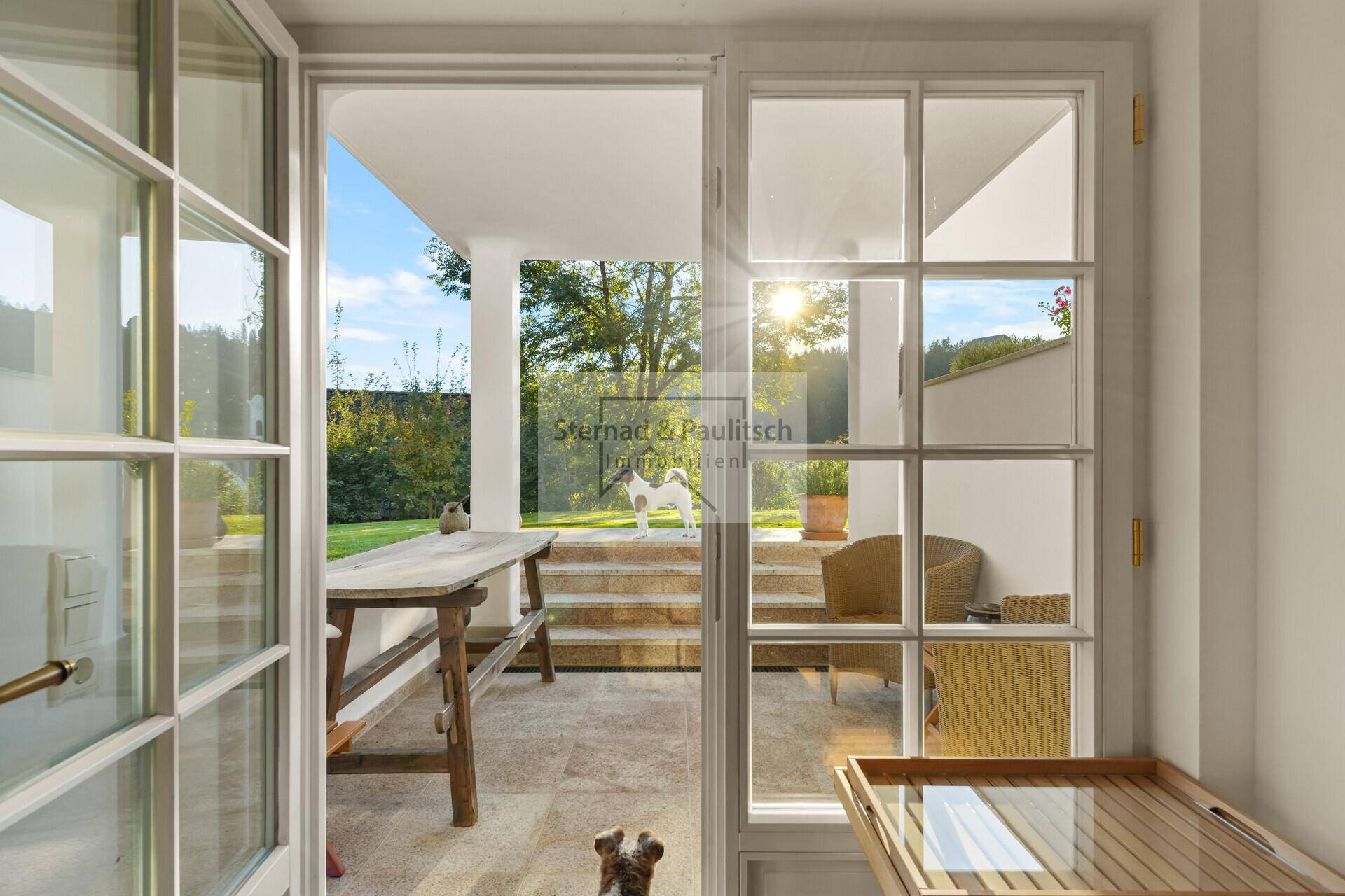 Heller Innenraum mit Zugang zu einer überdachten Terrasse und einem gepflegten Garten.