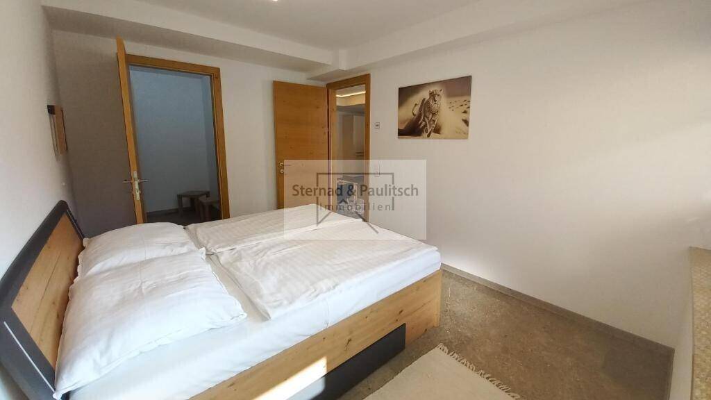 Helles Schlafzimmer mit Doppelbett, Holzboden und Zugang zu weiteren Räumen, einladend und funktional.